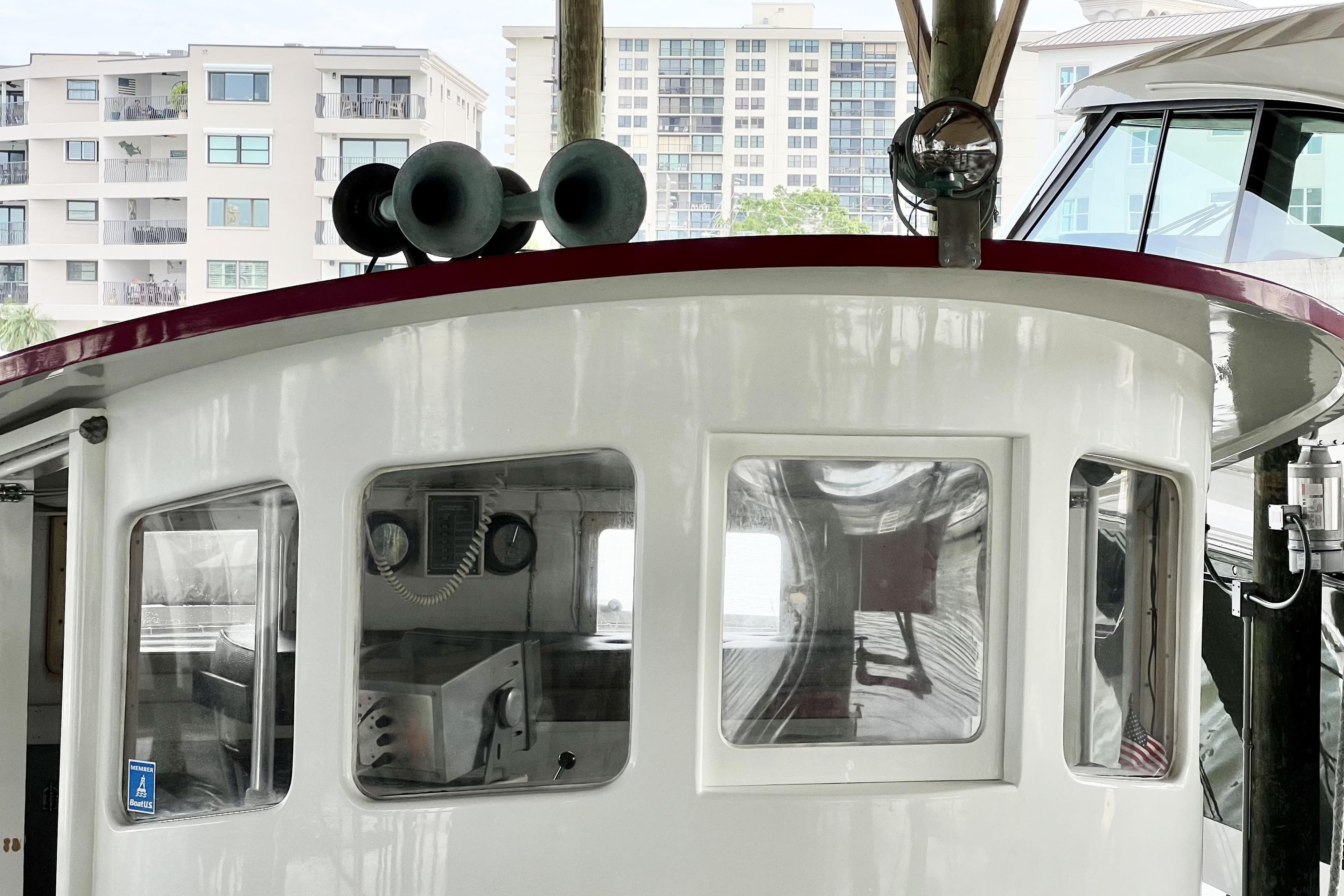 1972 custom tug boat cabin with windows, docked near modern buildings.