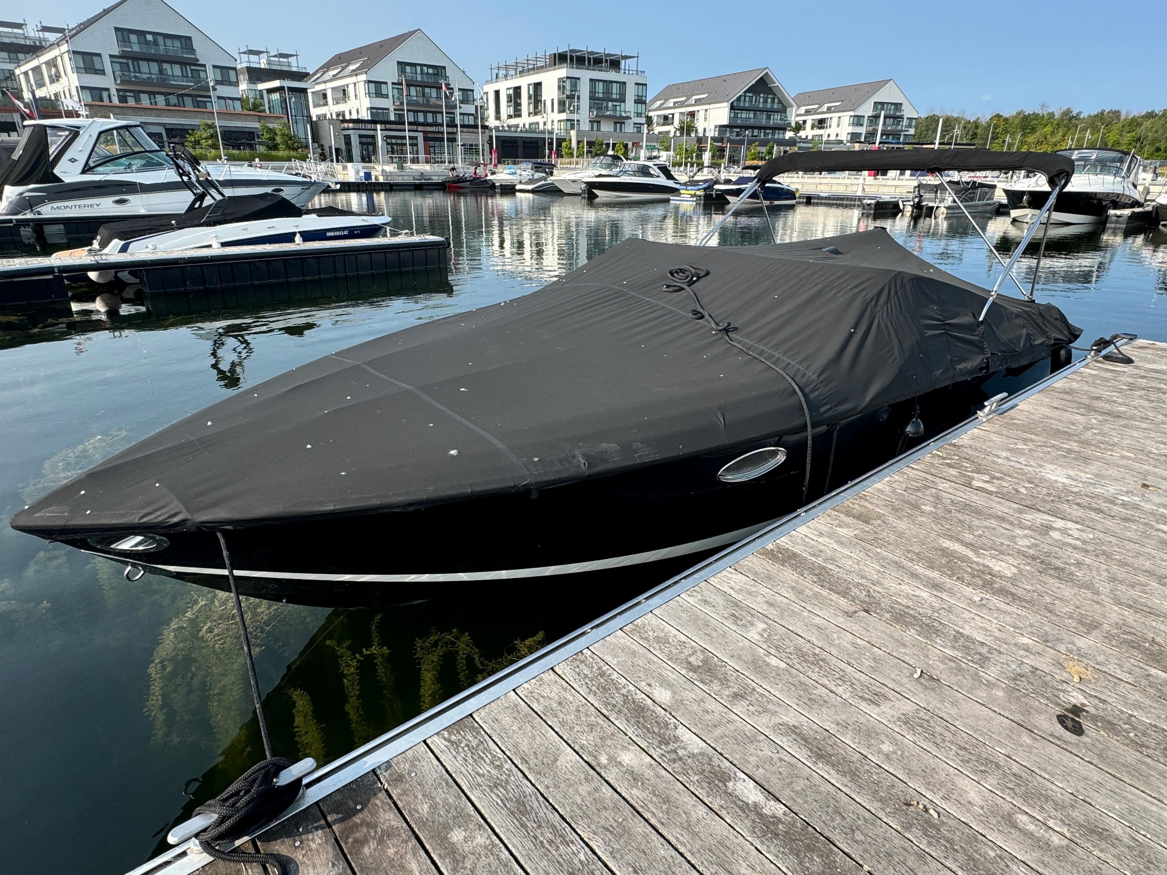 Covered 2002 Cobalt 263 boat docked at a marina with modern buildings in the background.