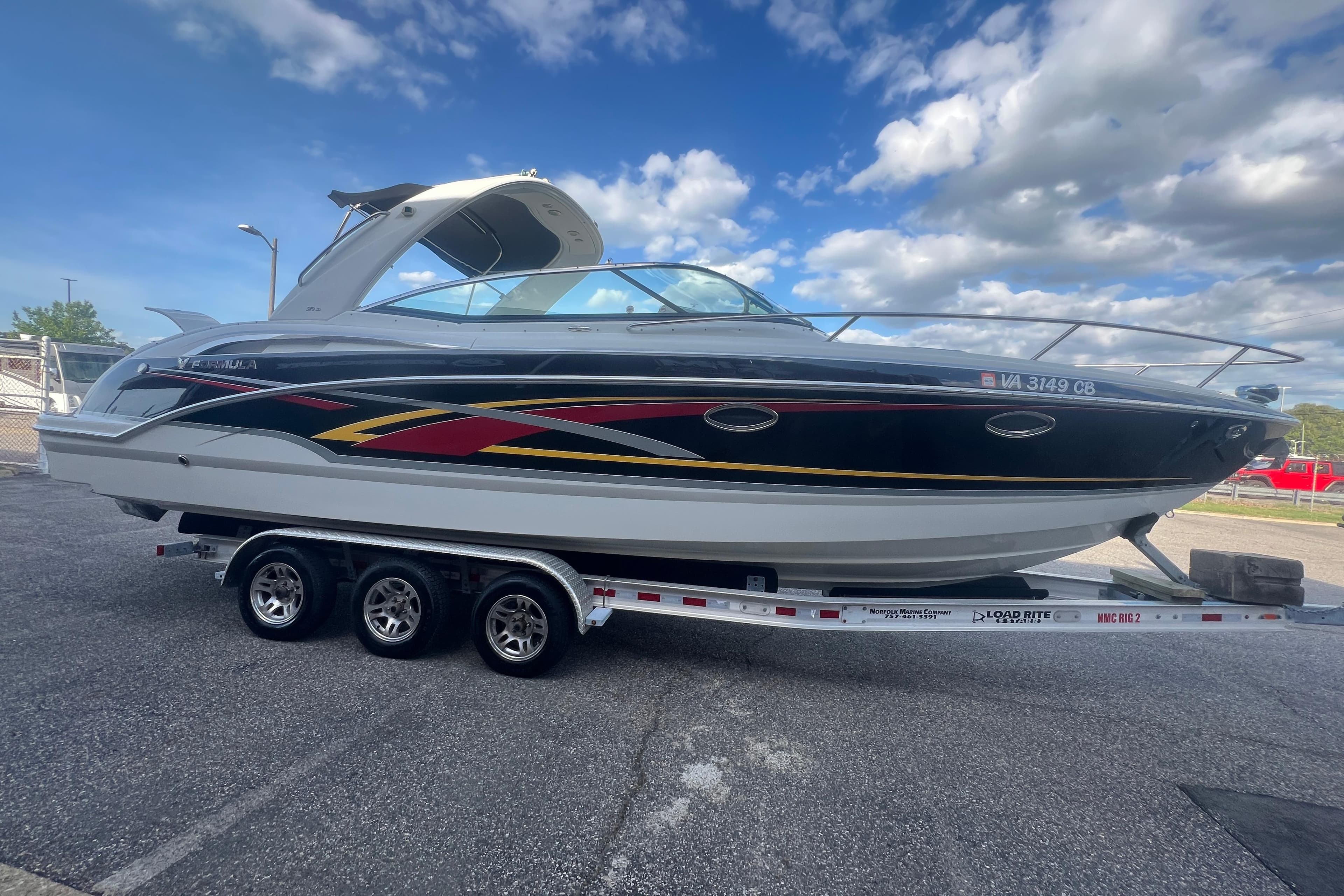 2008 Formula 310 Sun Sport boat on trailer under a partly cloudy sky.