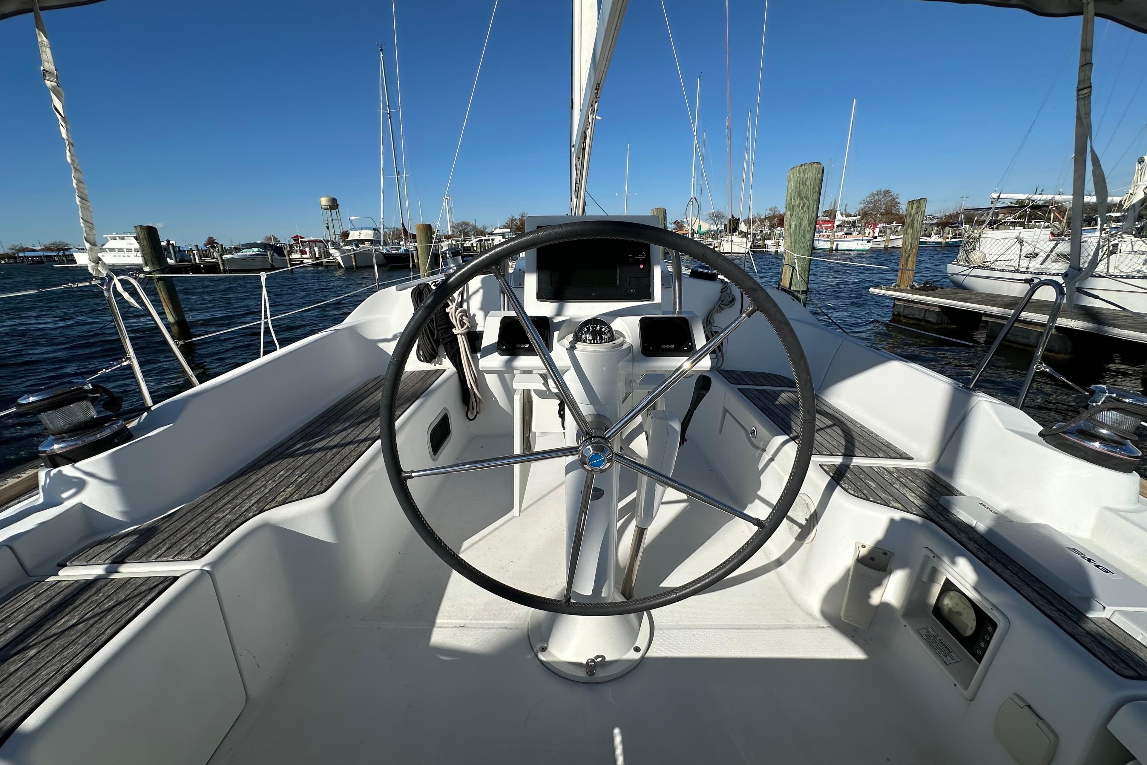 2015 Beneteau Oceanis 37 sailboat cockpit with steering wheel, docked in marina.
