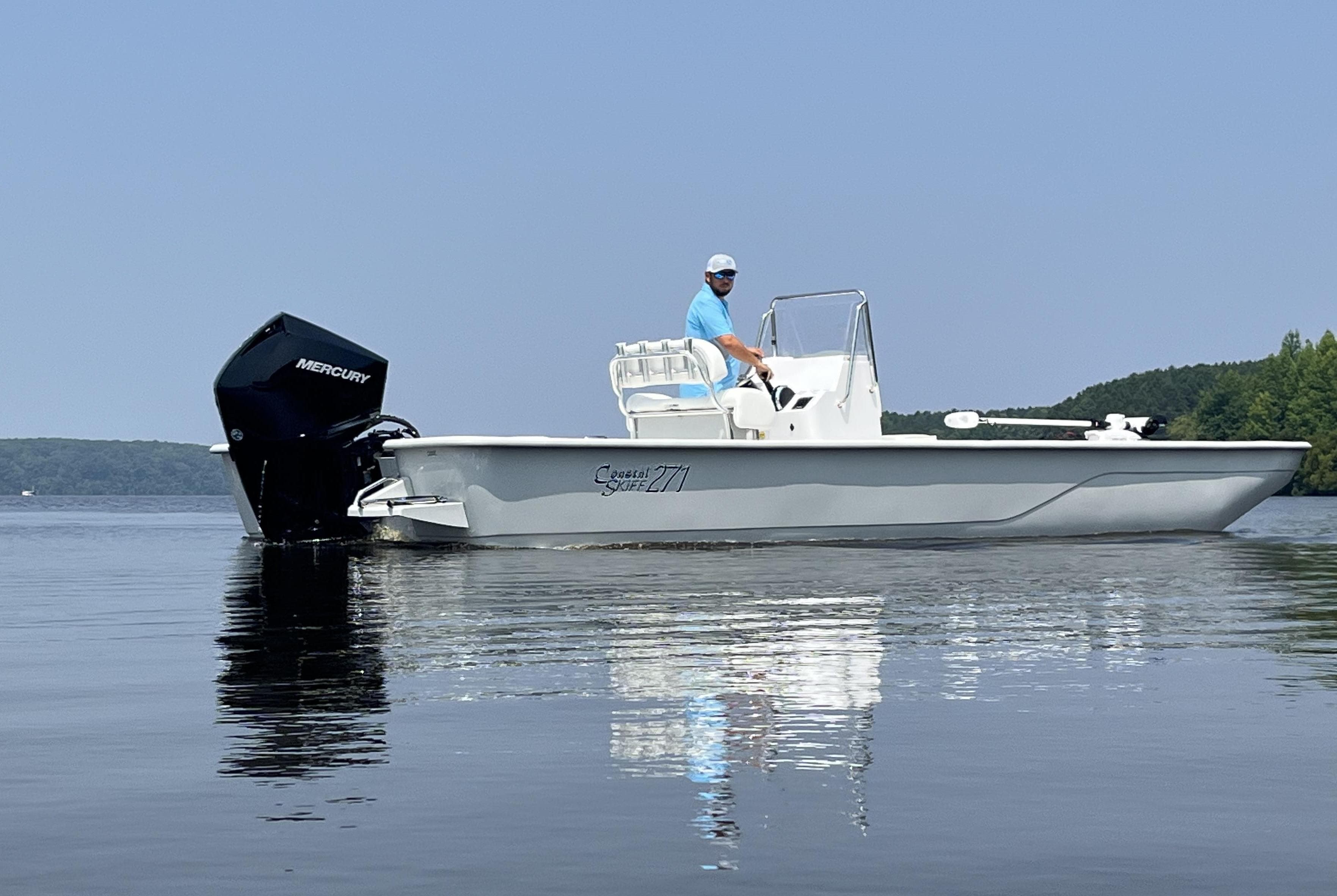 2024 Coastal Skiff 271 boat on calm water with Mercury outboard motor.
