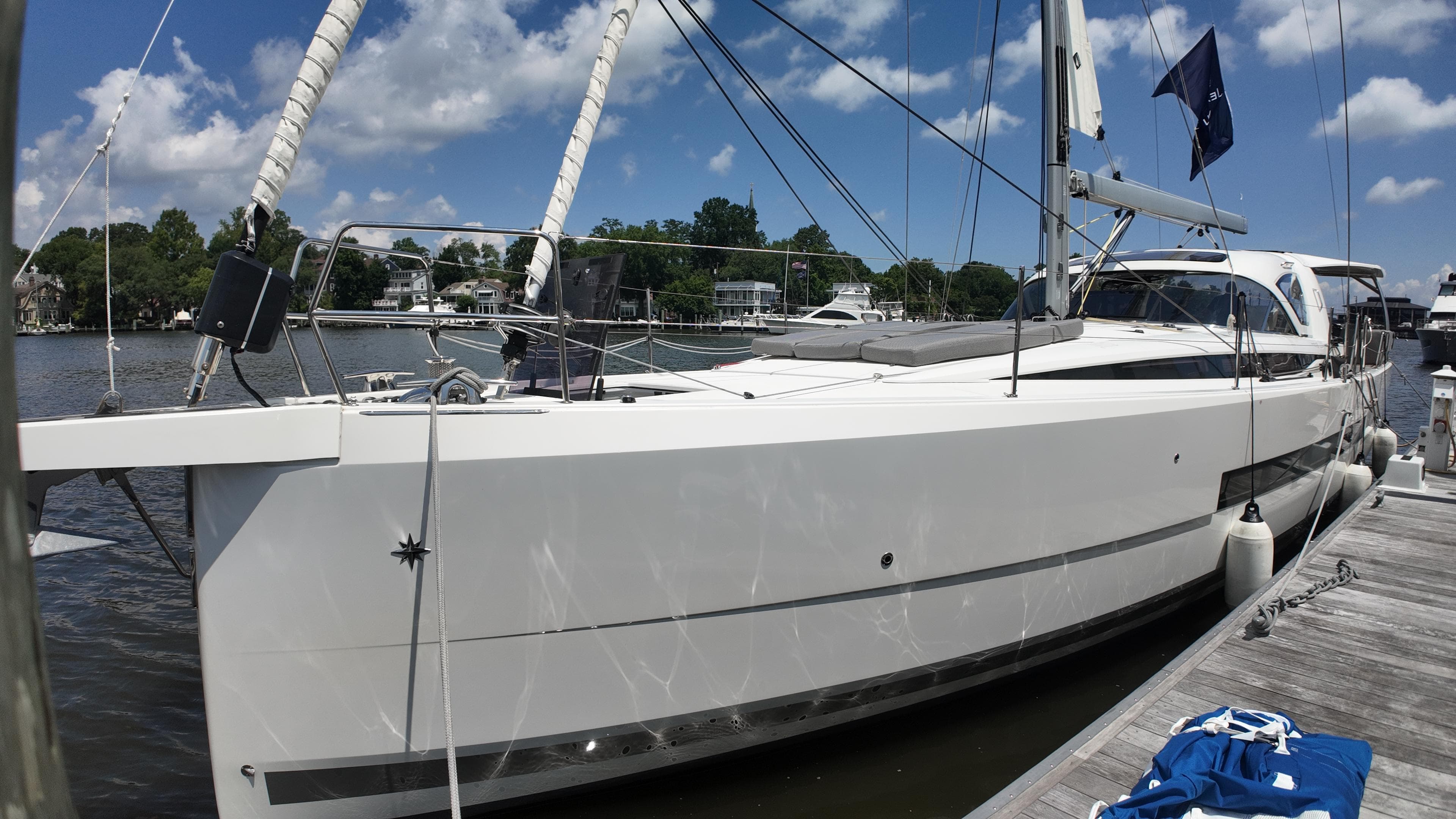 2024 Jeanneau 55 yacht docked, showcasing sleek design and modern features under a clear blue sky.
