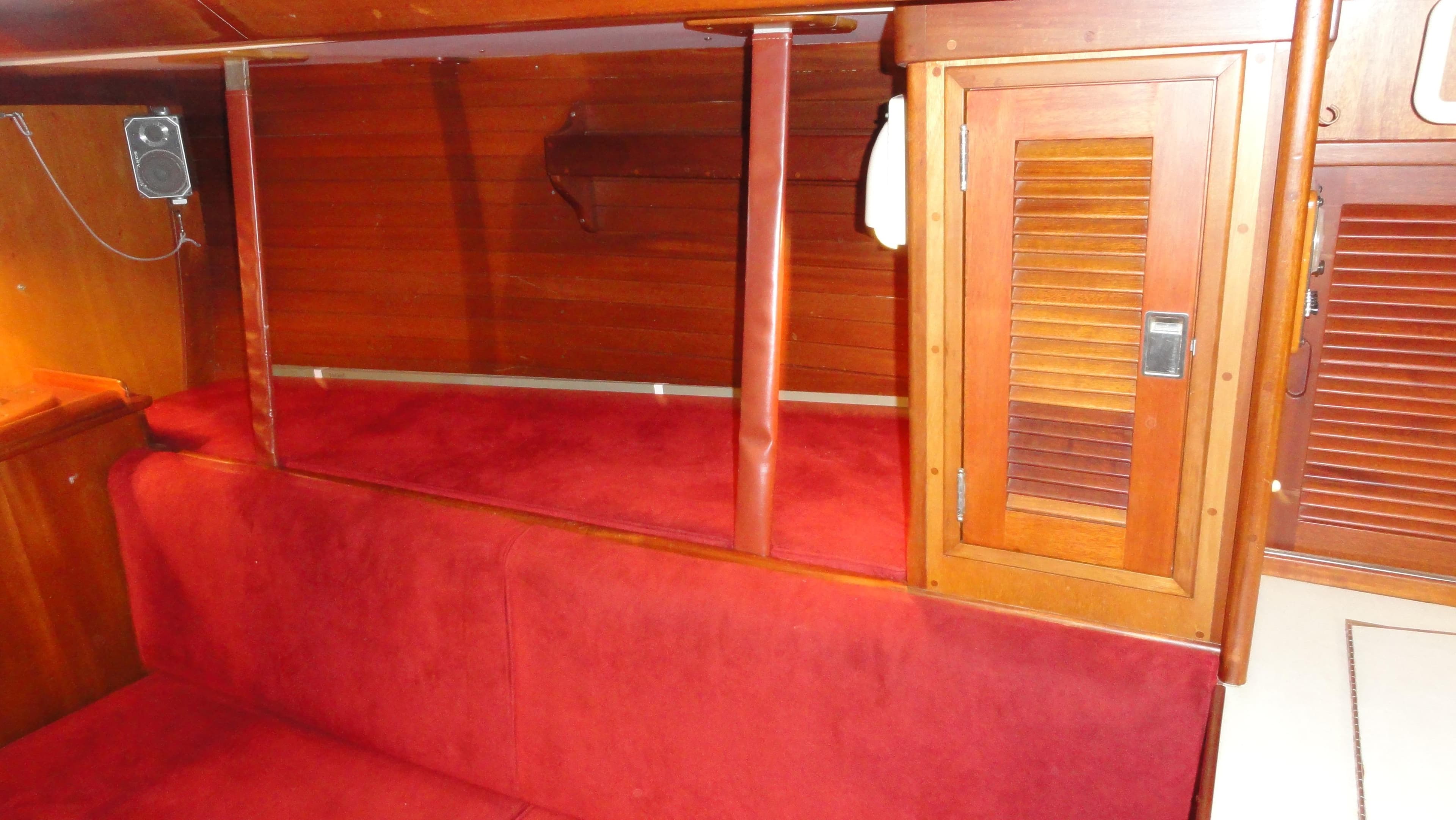 Interior of a 1980 Hinckley 43 boat with red seating and wooden cabinetry.