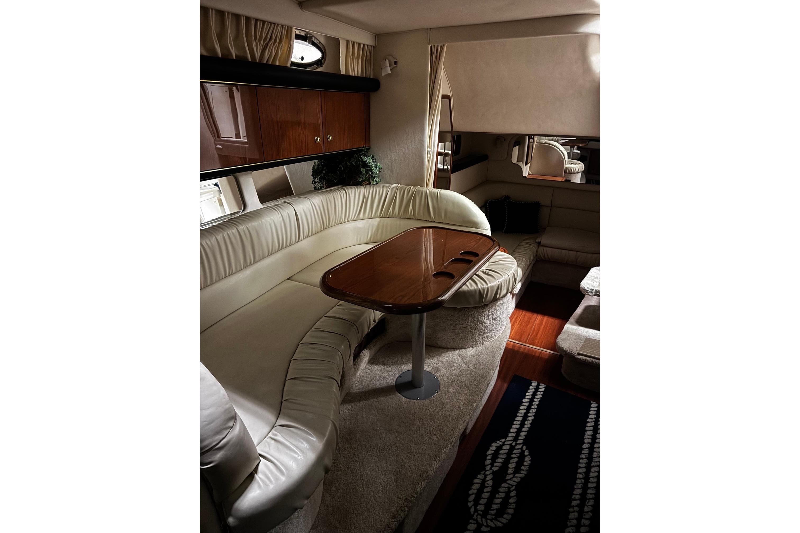 Luxurious interior of 1999 Sea Ray 340 Sundancer yacht with elegant seating and wooden table.