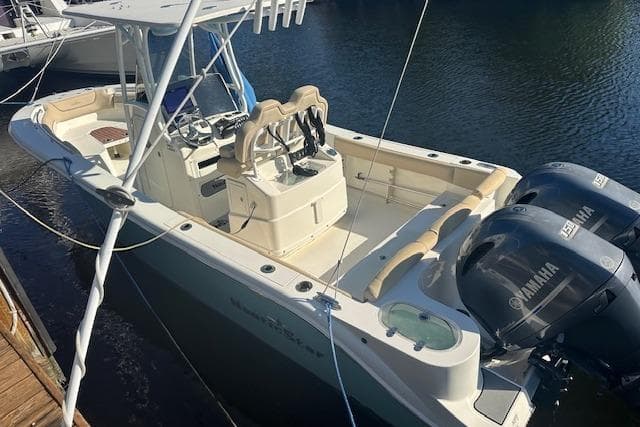 2018 NauticStar 2602 Legacy boat with dual Yamaha engines docked on calm water.