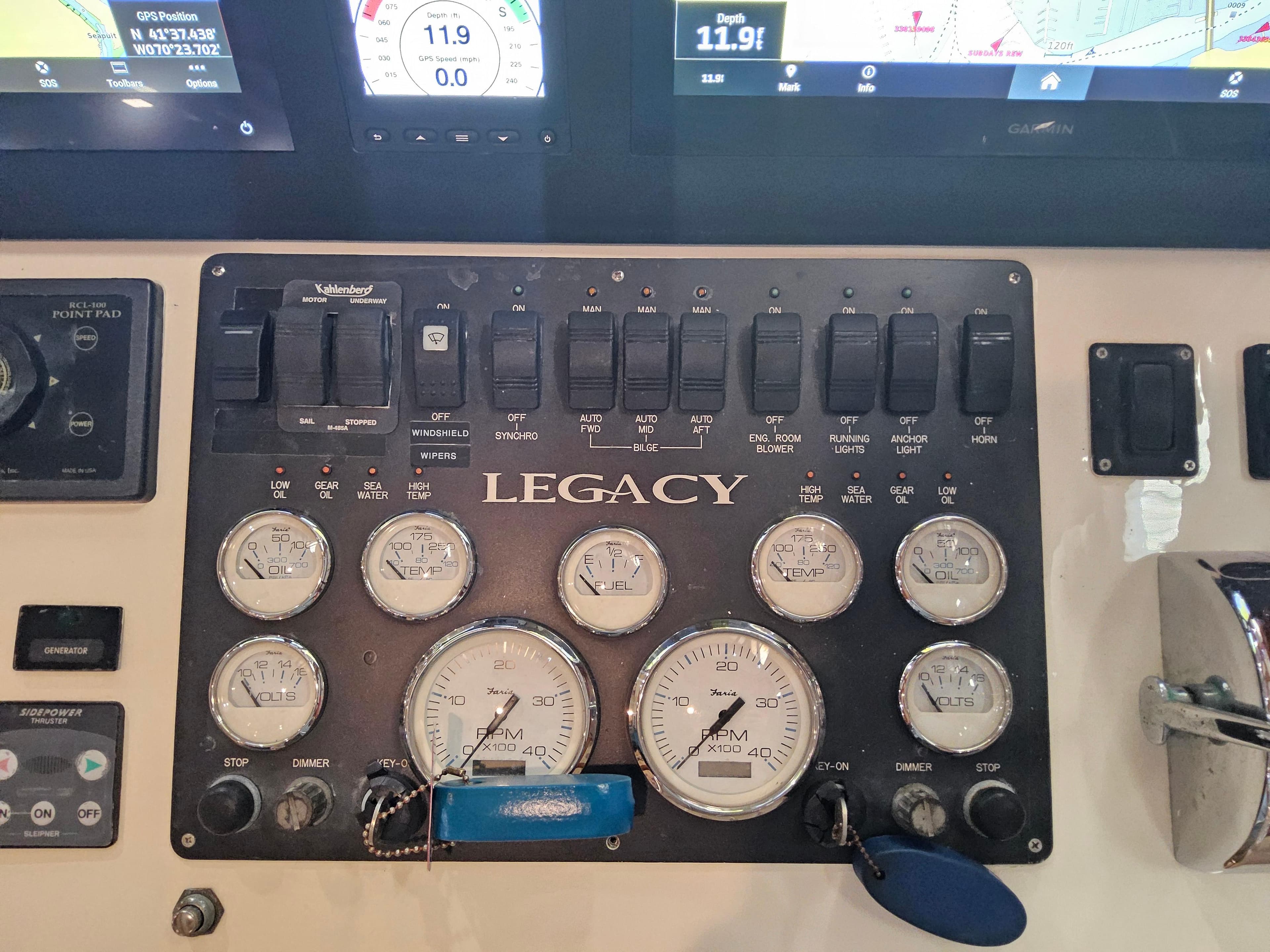 Control panel of a 2003 Legacy 40 Hardtop Express boat with gauges and switches.