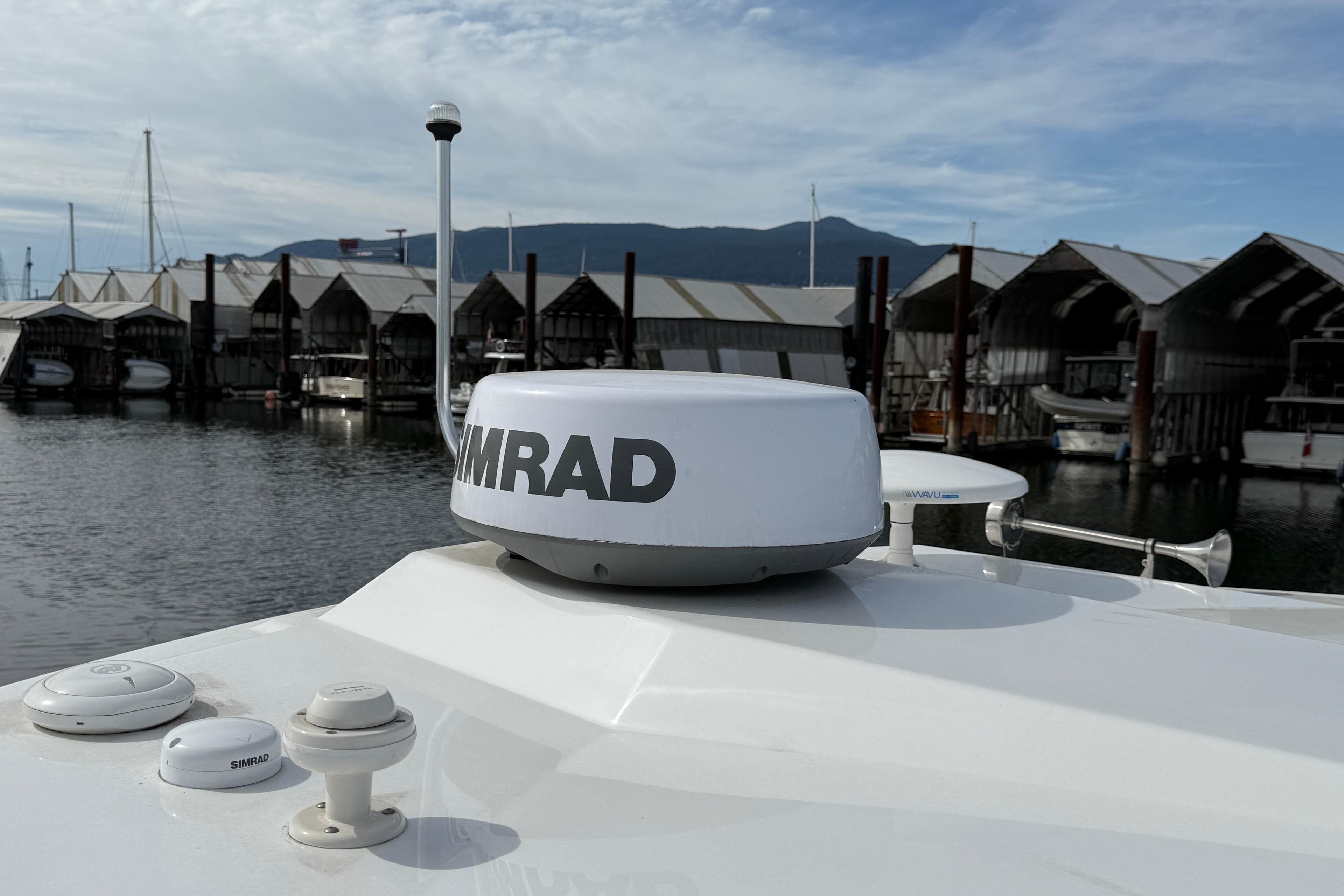 2022 Four Winns V355 Coupe OB with Simrad radar at marina, mountain backdrop.