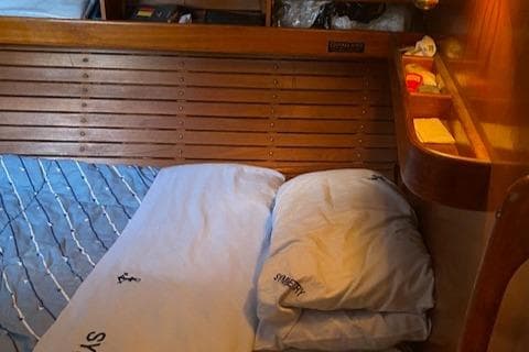 Cozy cabin interior of 1981 Nautor Swan 51 yacht with wooden paneling and bedding.