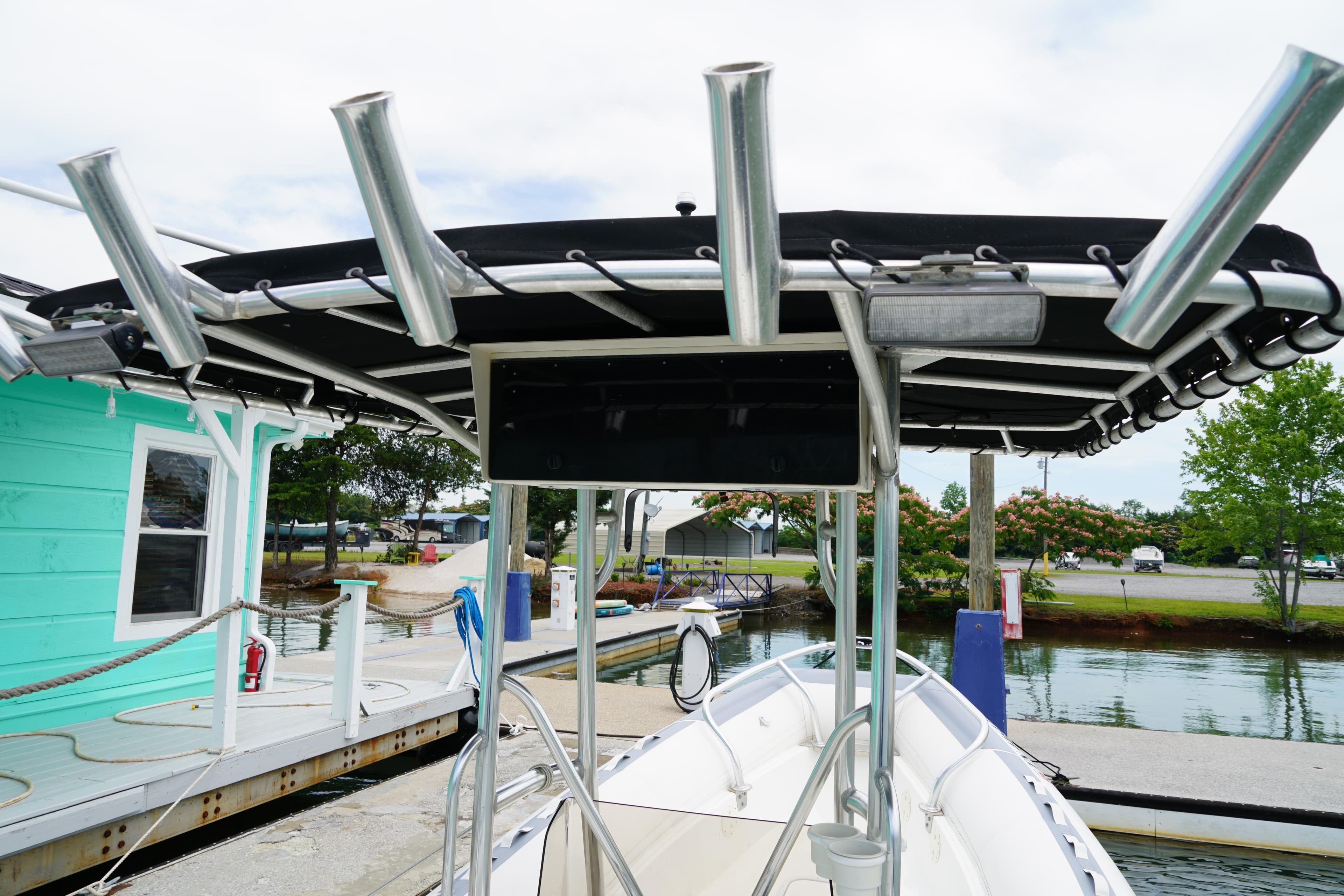 2003 Novurania 24 boat with rod holders docked near a turquoise building.