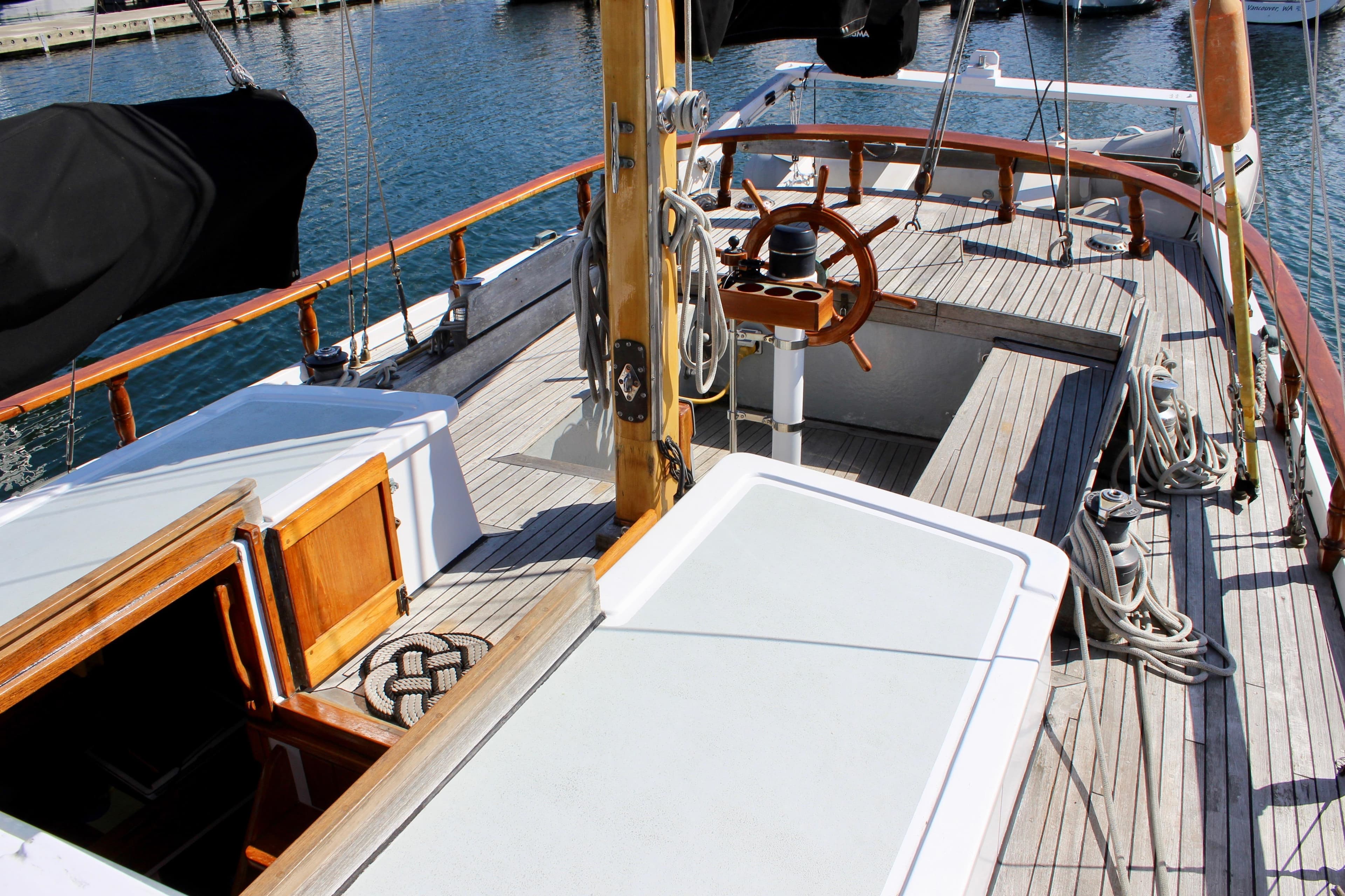 1975 William Garden Porpoise sailboat deck with wooden steering wheel and nautical ropes.