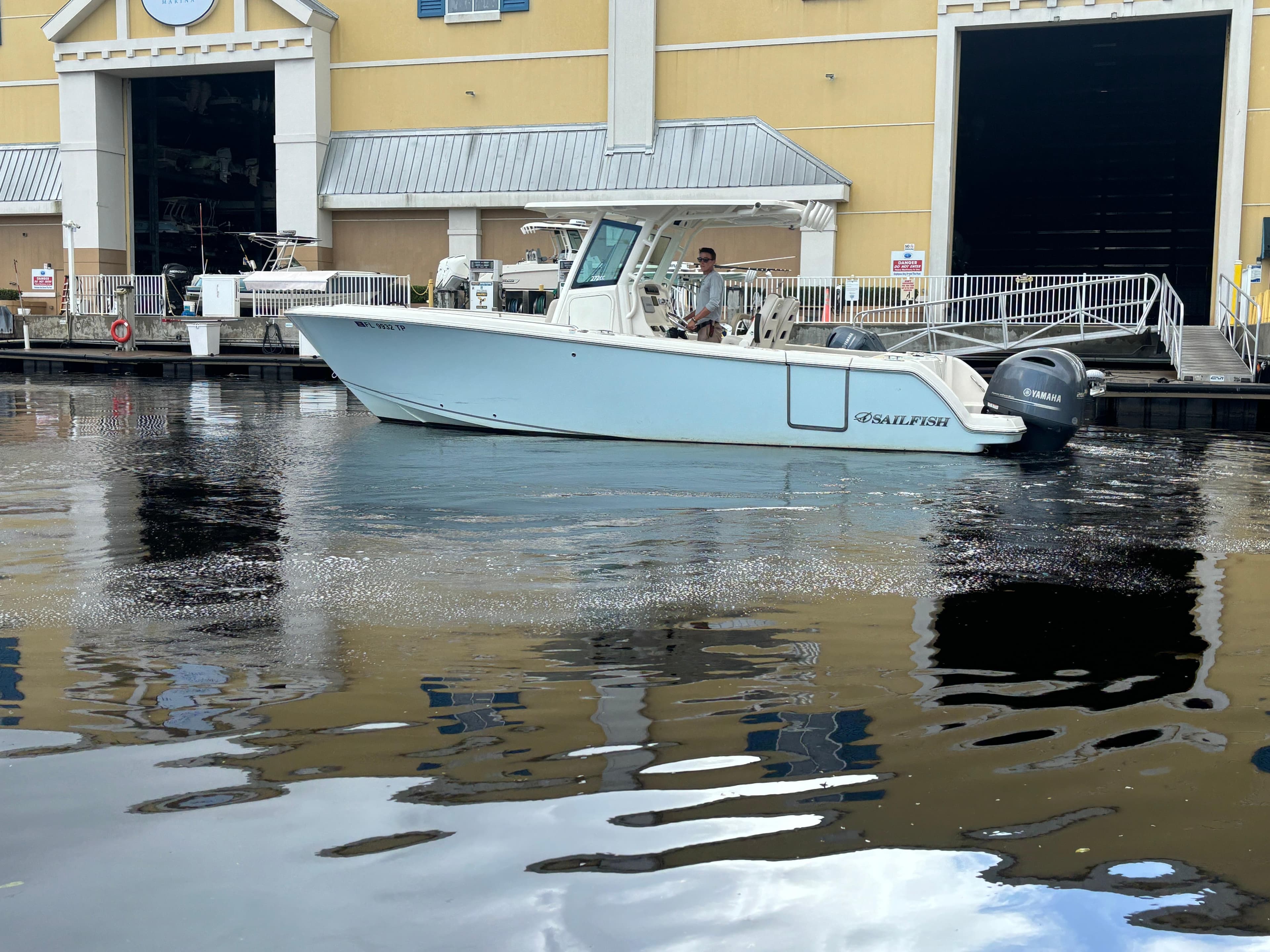 2023 Sailfish 272 CC boat docked near a waterfront building.
