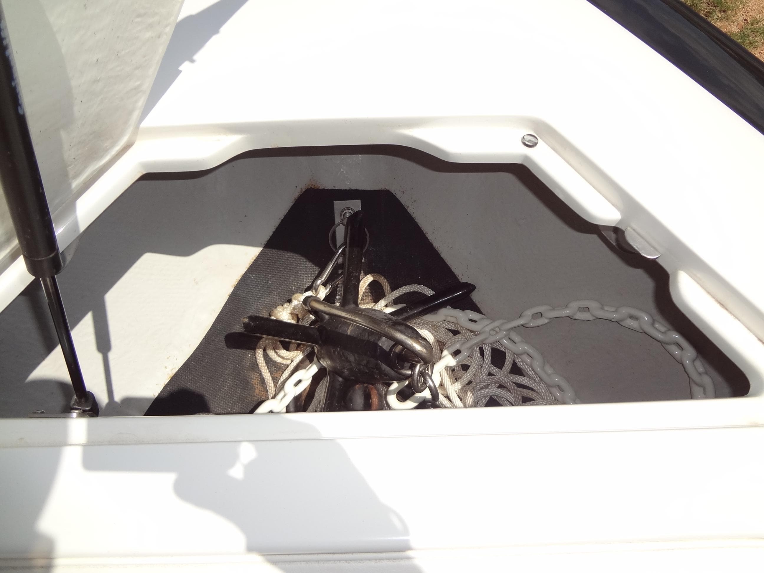Anchor storage compartment on a 2004 Cobalt 240 boat, featuring chain and rope.