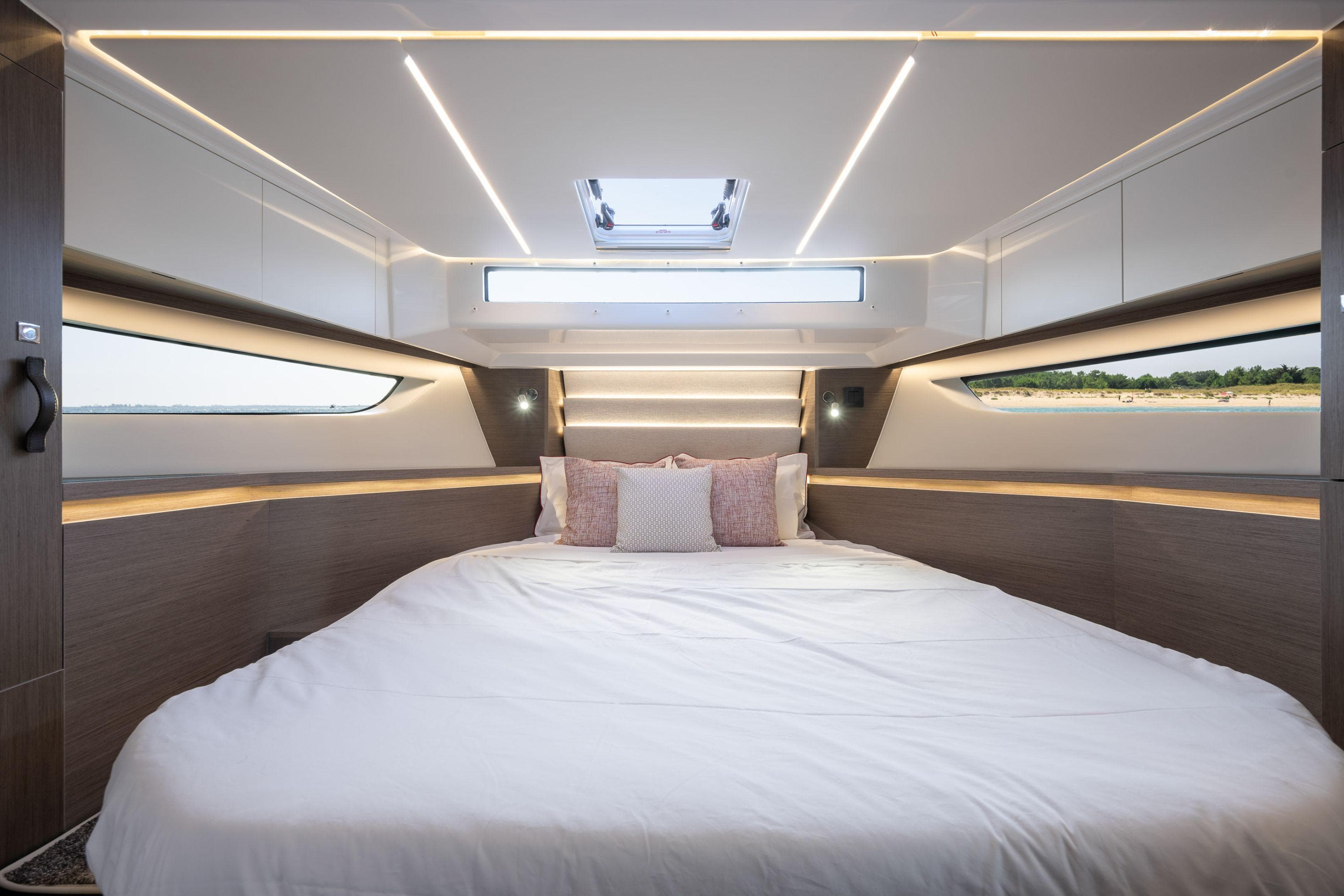 Luxurious cabin interior of 2025 Jeanneau NC 1295 Coupe with modern lighting and large bed.