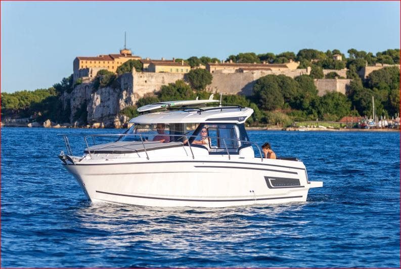 2024 Jeanneau NC 795 boat cruising near a historic coastal fort.