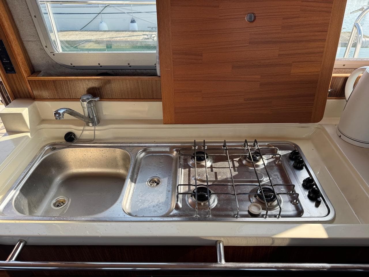 2003 Corvette 320 boat kitchen with sink, stove, and wooden accents.