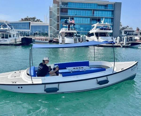2023 Vision Marine Technologies Fantail 217 boat on water, with blue canopy and seating.