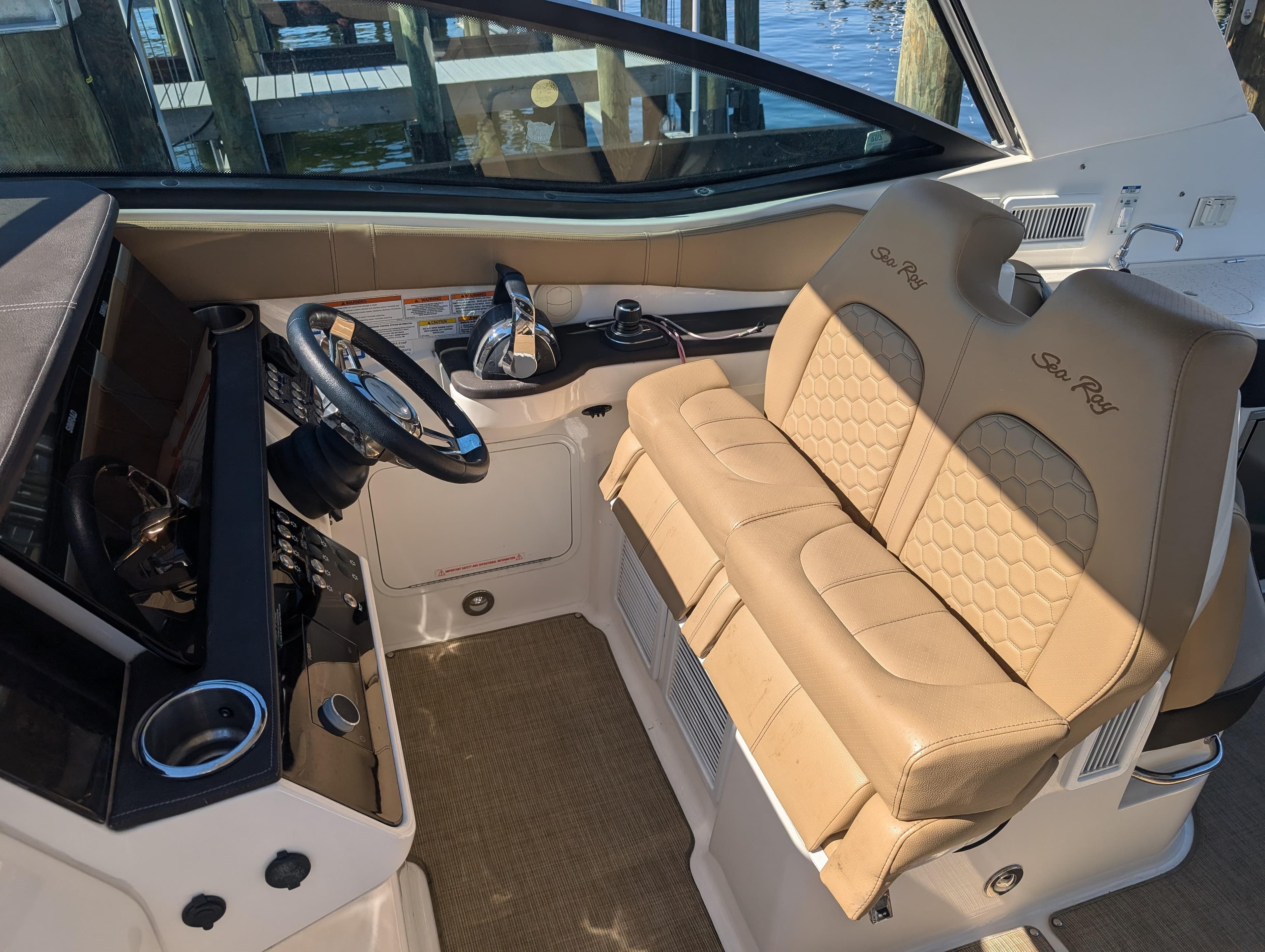 2019 Sea Ray Sundancer 320 cockpit with beige leather seats and modern controls.