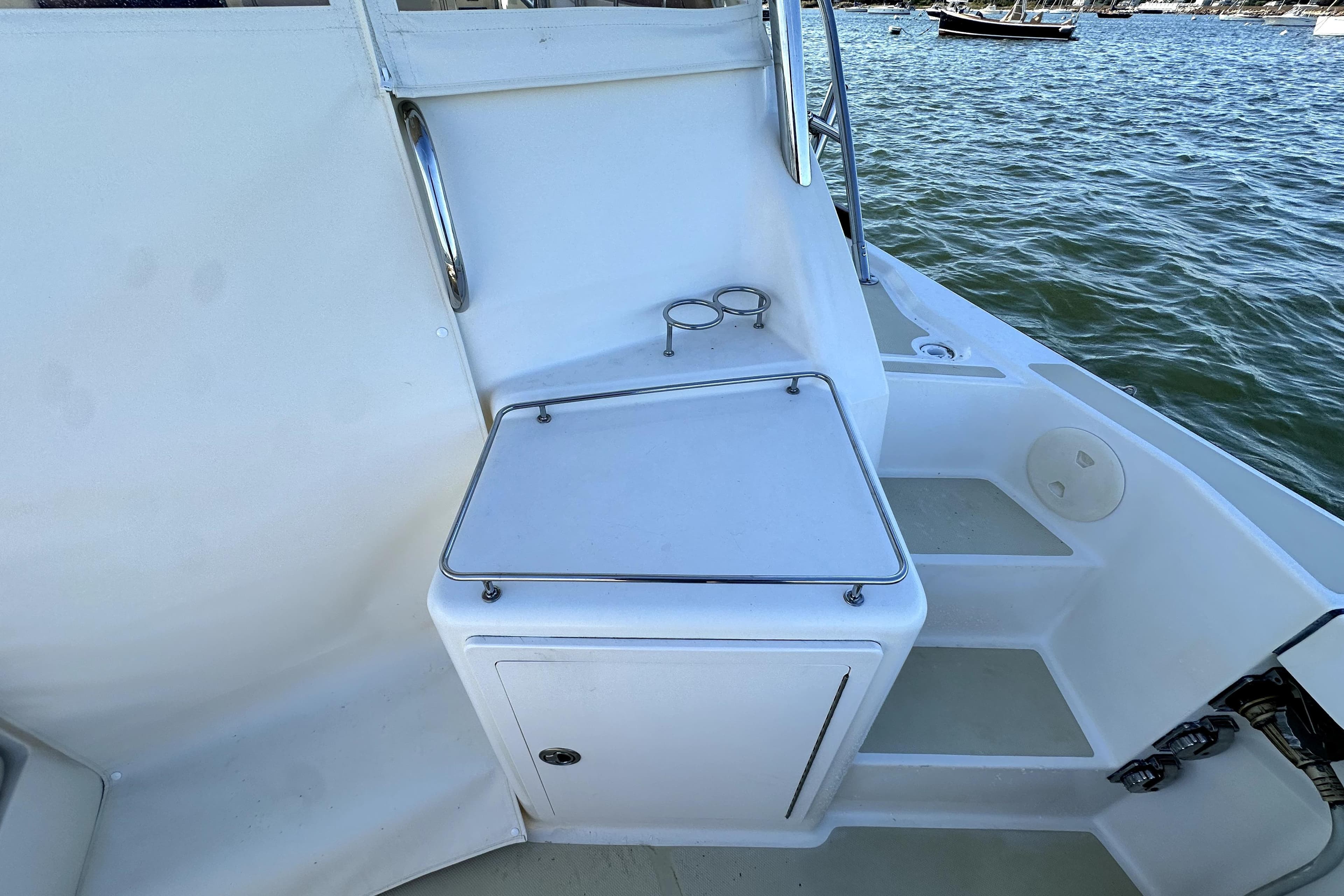 2007 Sabre 34 Express boat deck with storage compartment and cup holders by the water.