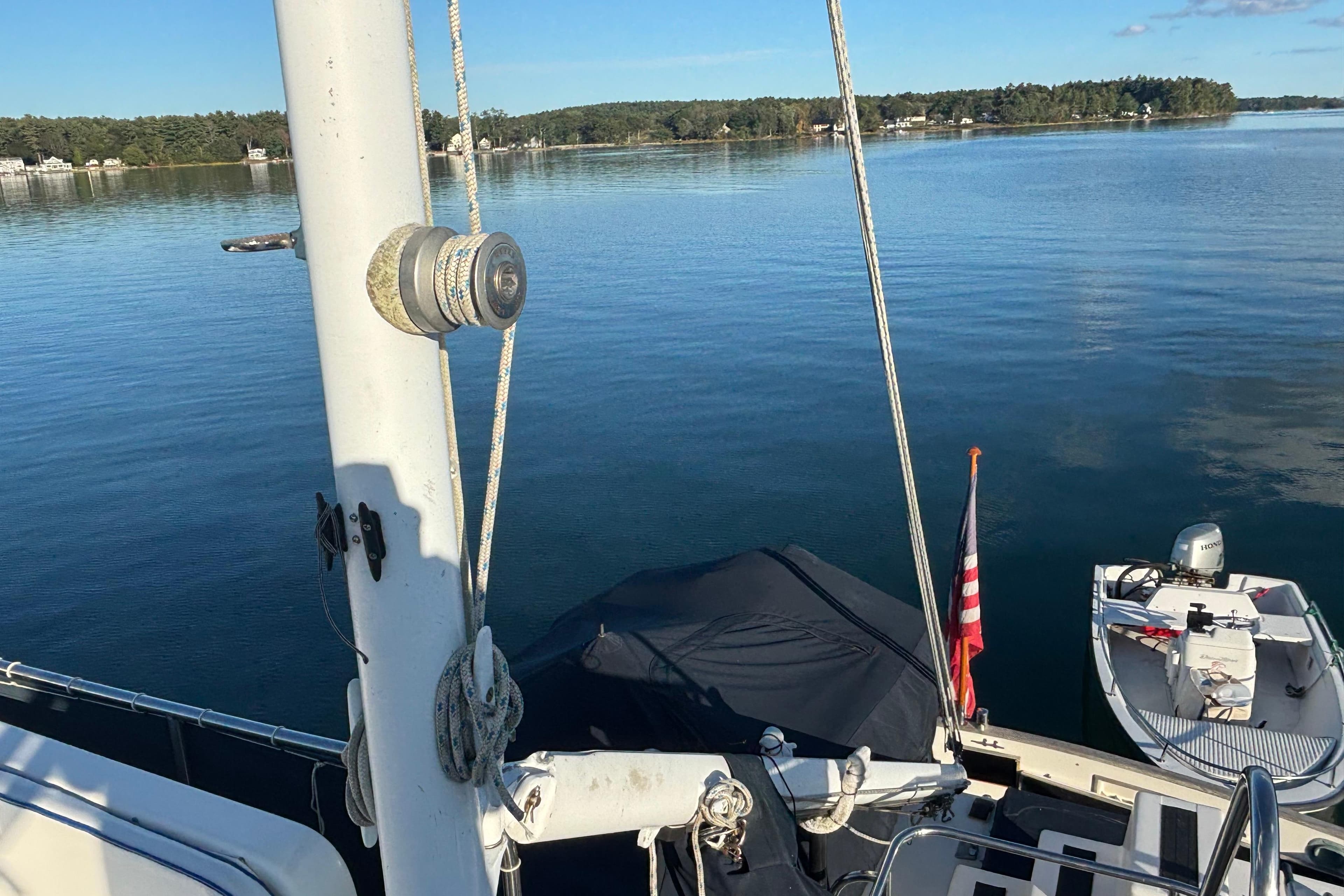 1989 Grand Banks 46 Classic yacht on serene lake with American flag and small boat.