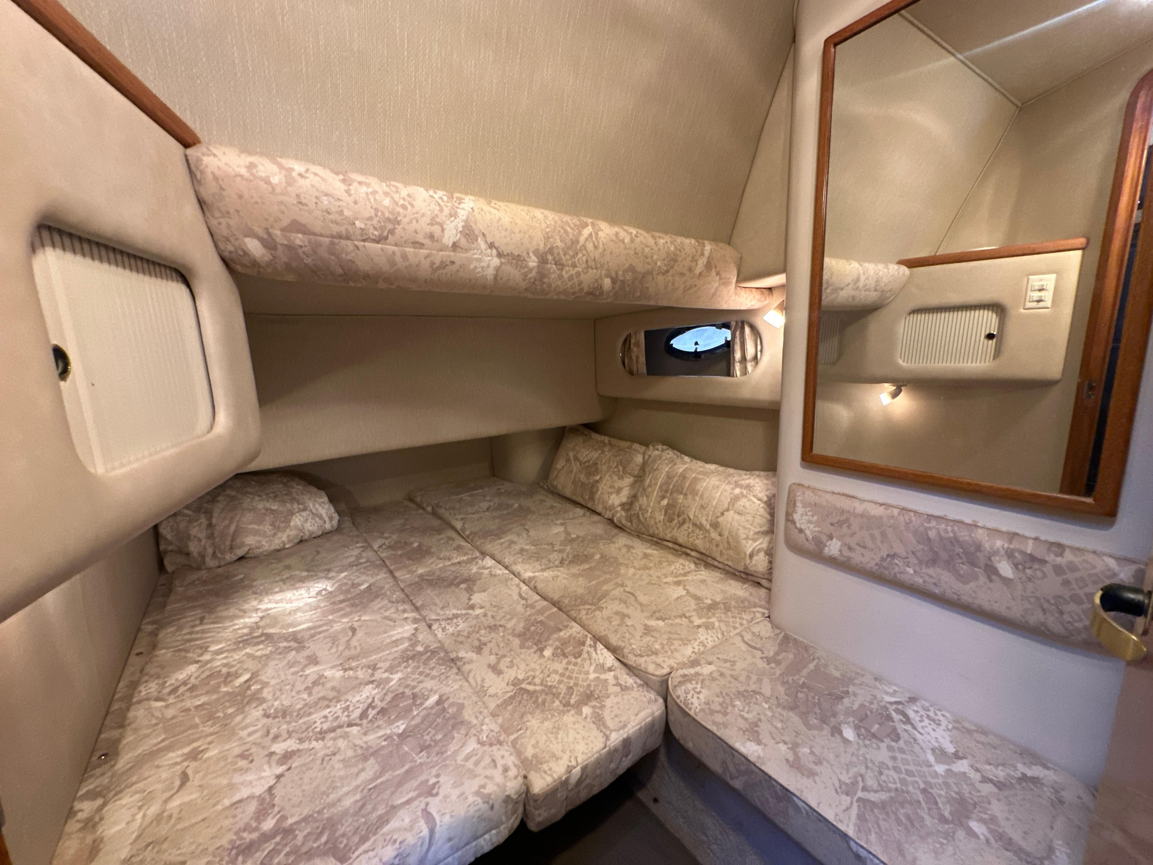 1997 Sea Ray 400 Sedan Bridge cabin with cozy bedding and mirror.