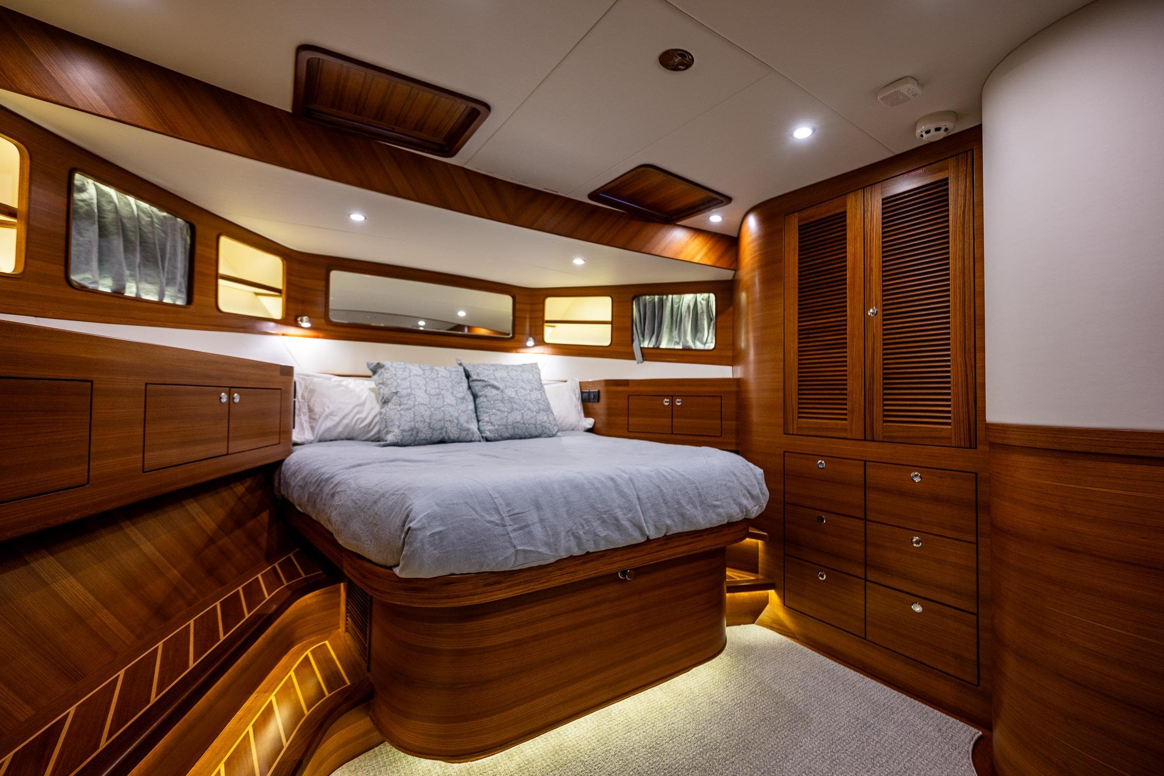 Luxurious cabin interior of 2026 Fleming 55 Pilothouse yacht with wood finish and cozy bed.