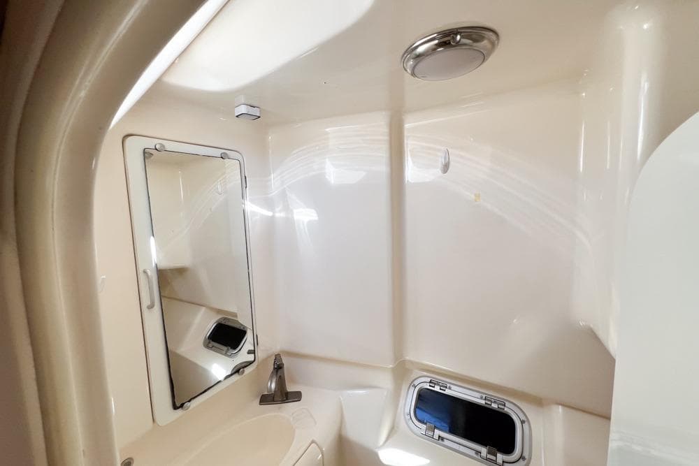 Compact bathroom in a 2000 Leopard 38 yacht, featuring a mirror and porthole.