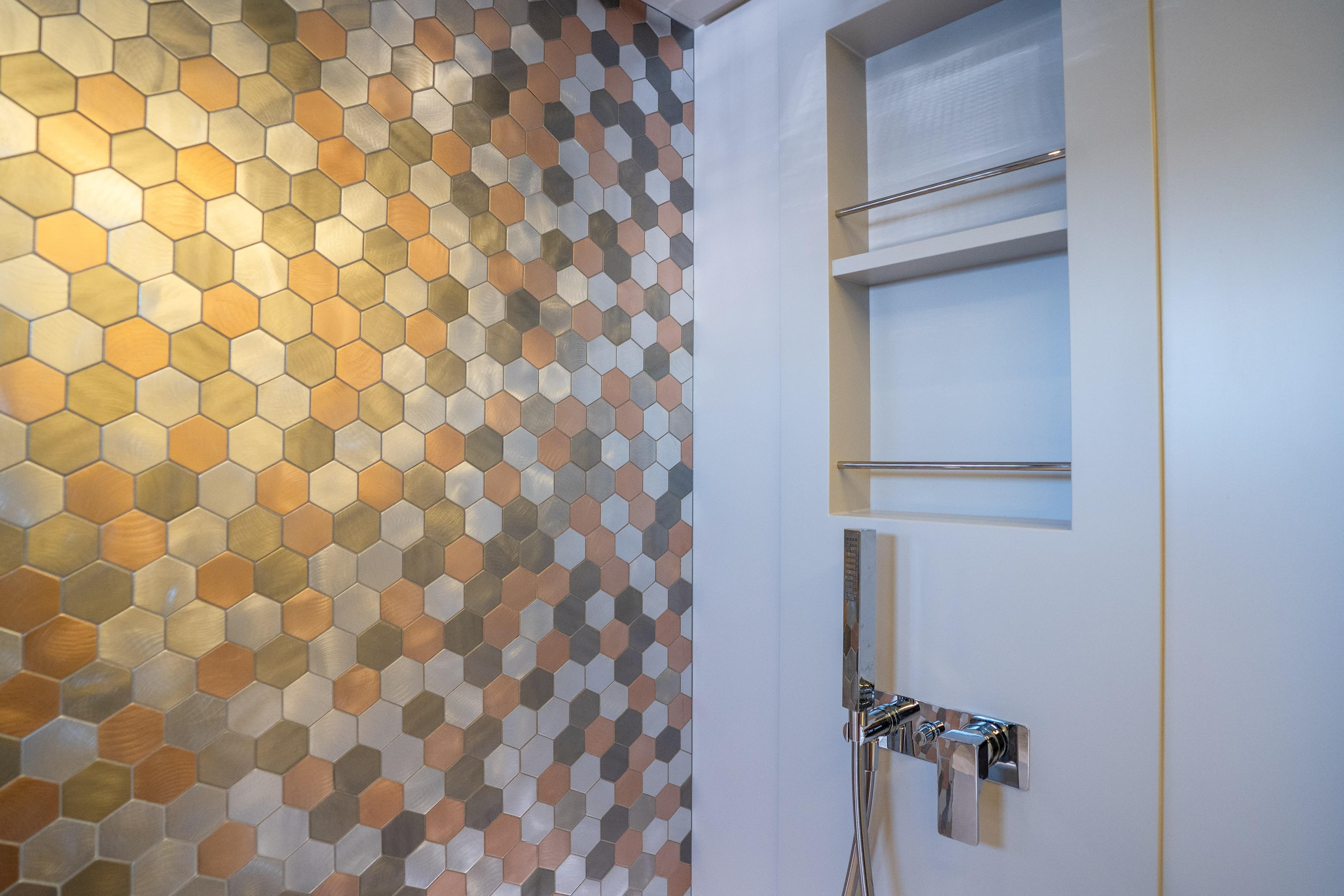Luxurious bathroom with hexagonal metallic tiles in a 2024 Pershing 7X yacht.