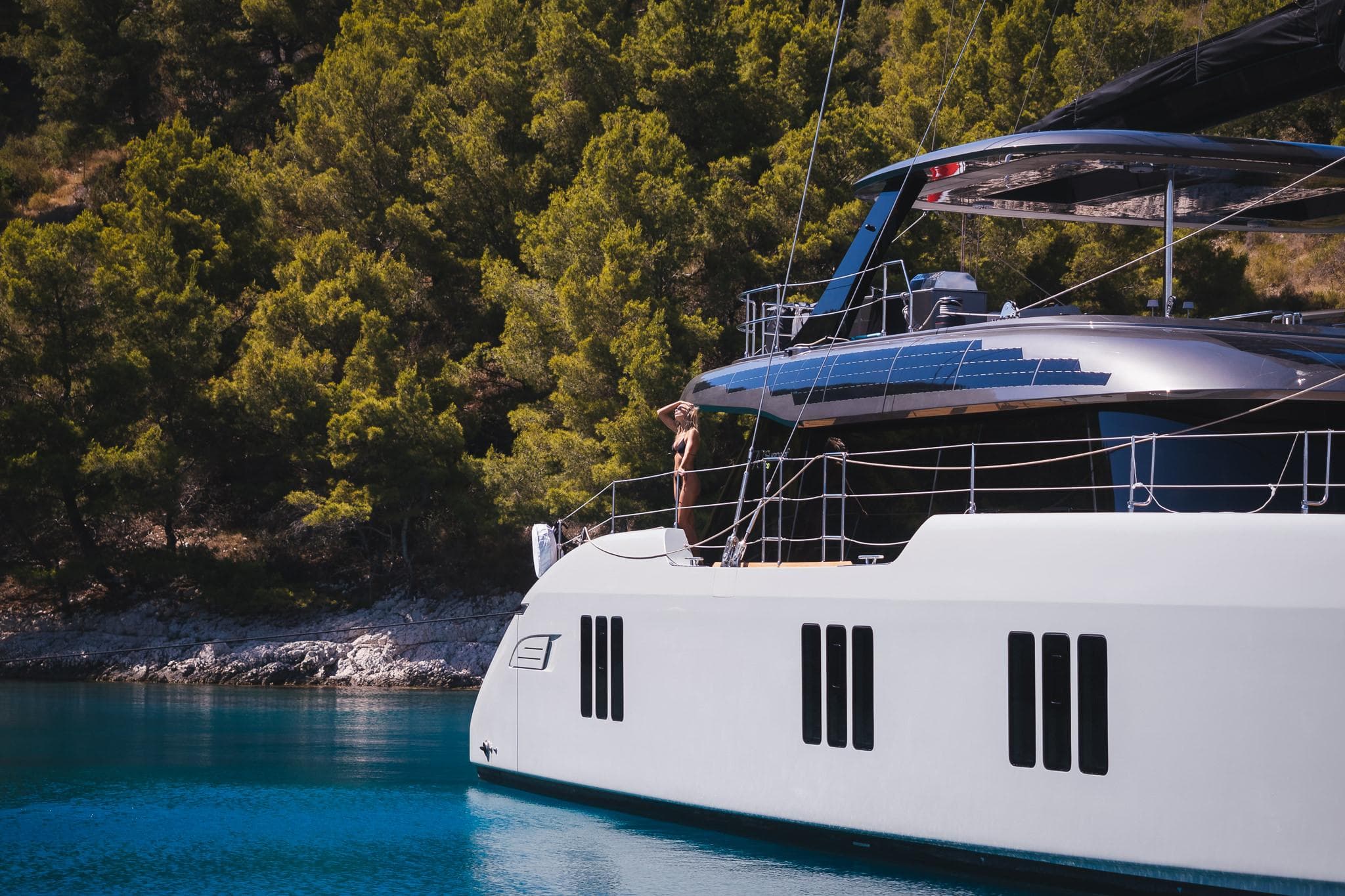 Luxury Sunreef 70 Eco yacht sailing near lush green coastline, 2024 model.