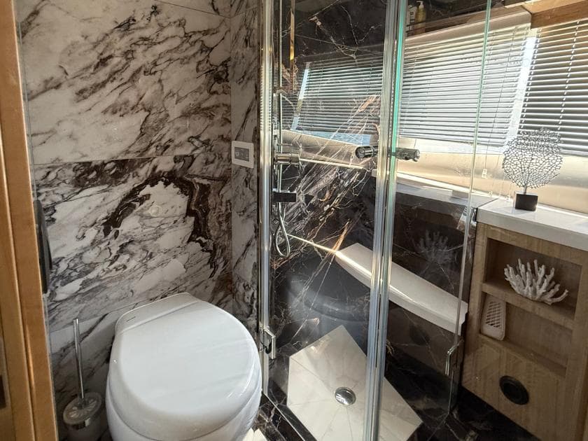 Luxurious bathroom in 2021 Galeon 700 Sky yacht with marble walls and glass shower.