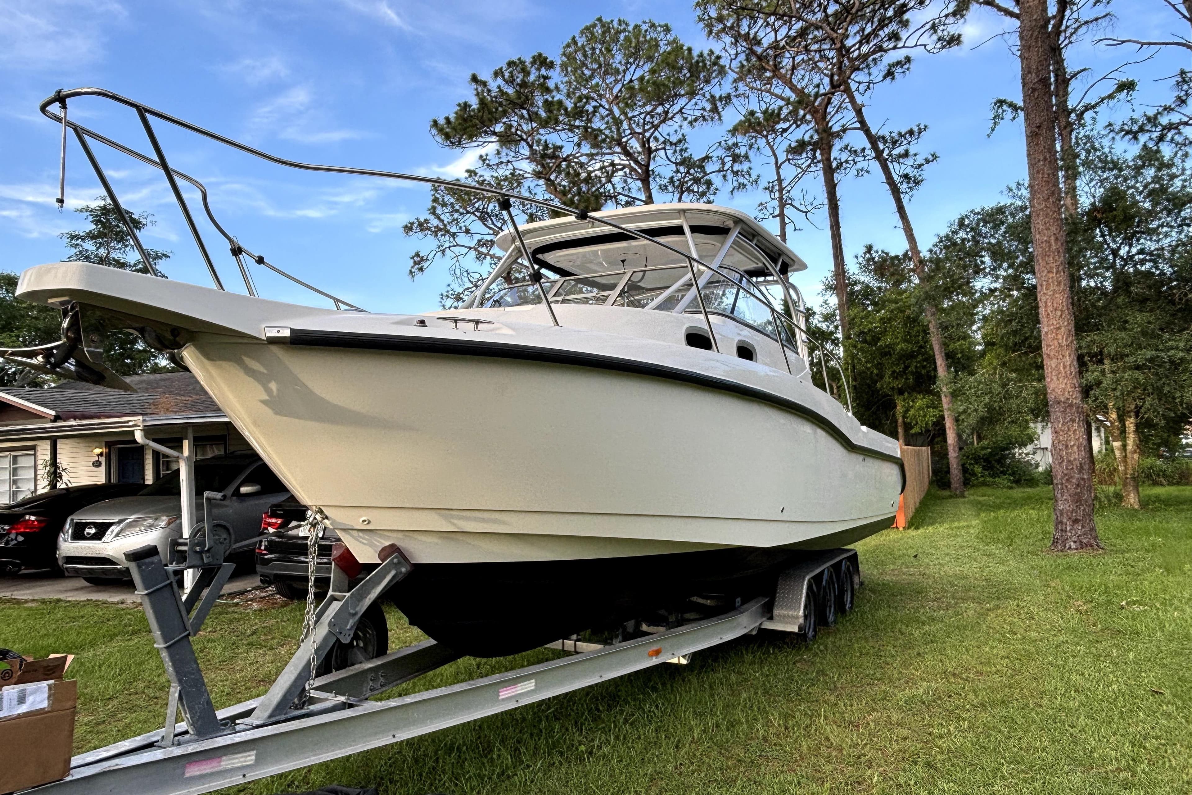 2005 Boston Whaler 305 Conquest boat on trailer, parked in a grassy yard.