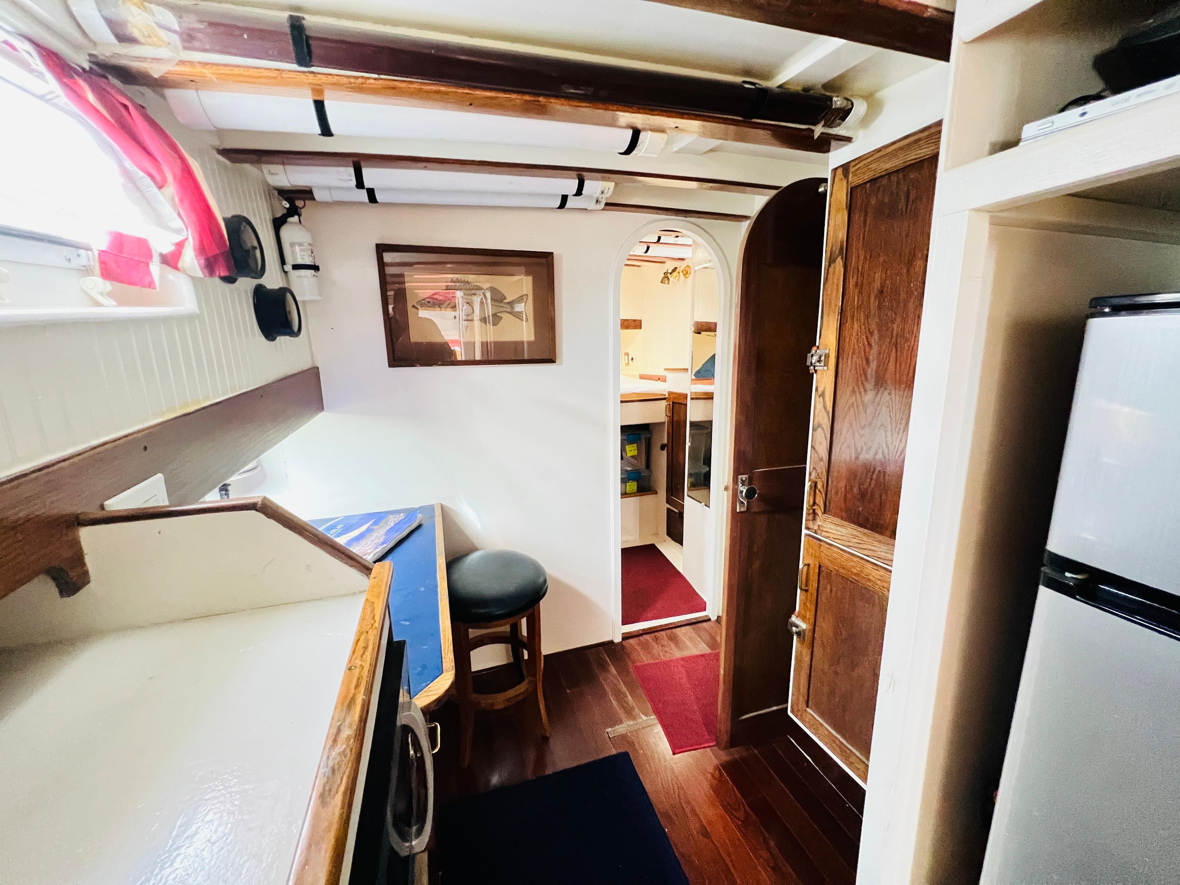 Interior of 1955 Colin Archer 42 sailboat with wooden finishes and compact kitchen.