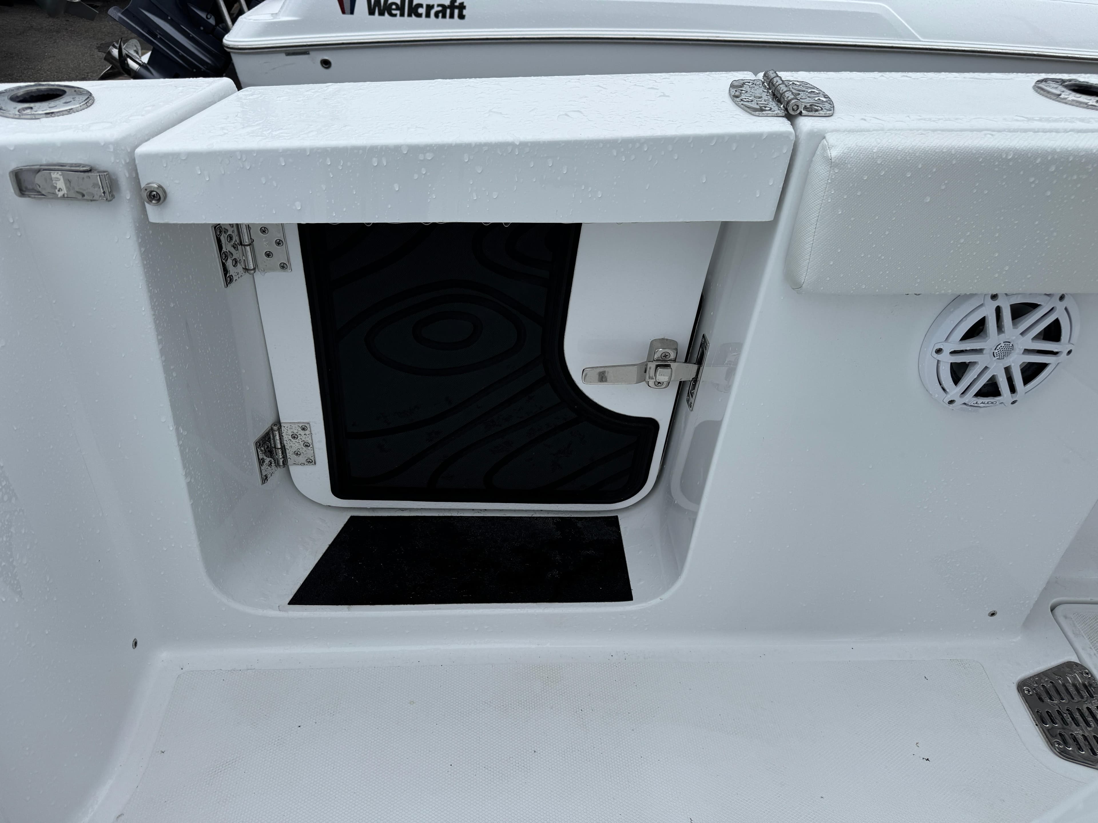 2025 Wellcraft 263 Fisherman boat storage compartment with open hatch and speaker.