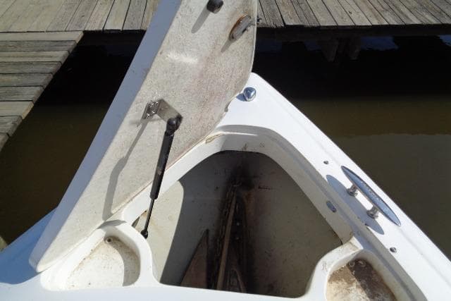 Open storage compartment on a 2006 Cobalt 282 boat near a wooden dock.