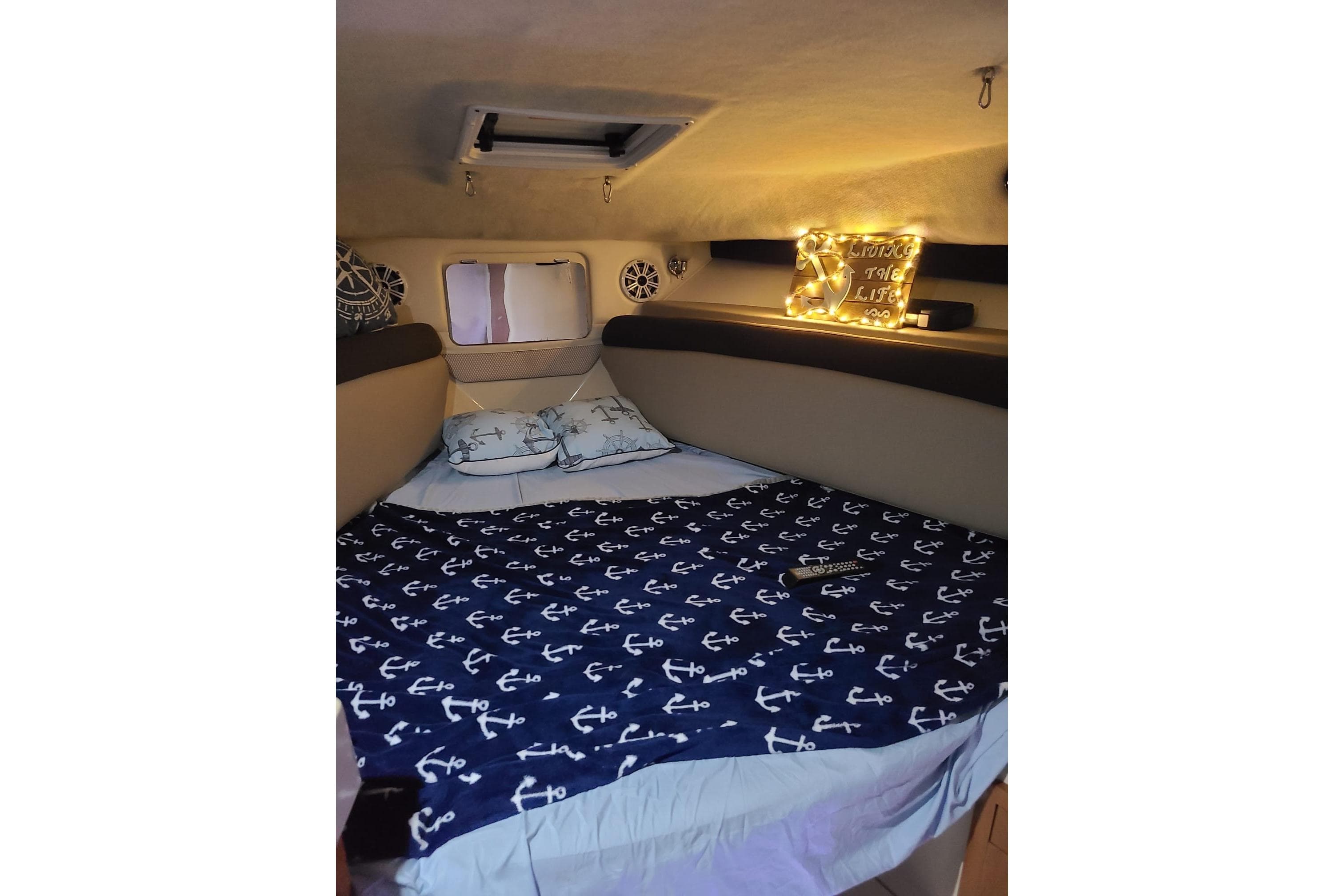 Cozy cabin interior of 2004 Wellcraft 290 Coastal with nautical-themed bedding and ambient lighting.