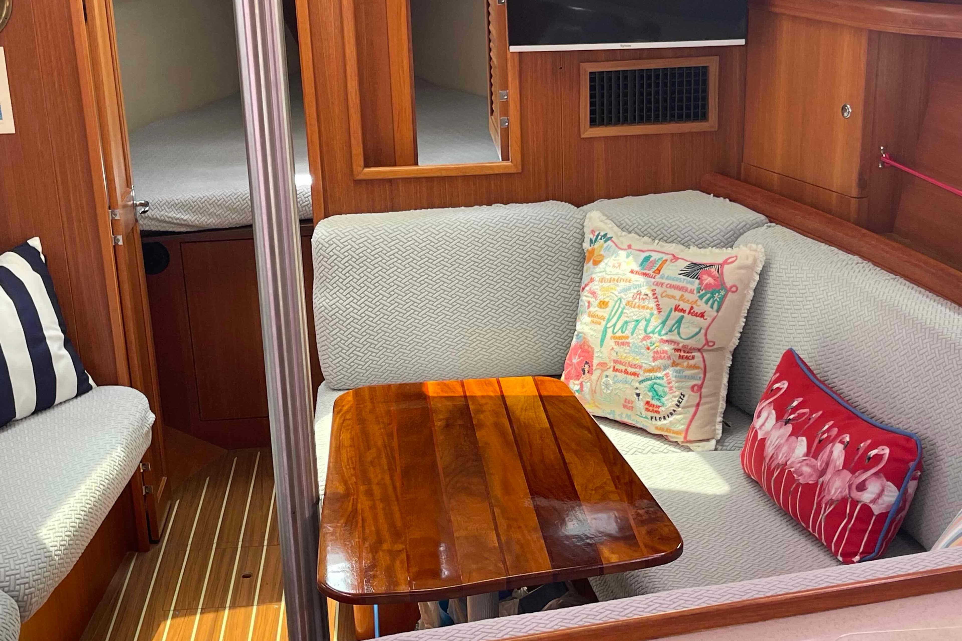 Cozy interior of 2004 Hunter 36 sailboat with cushions and wooden table.