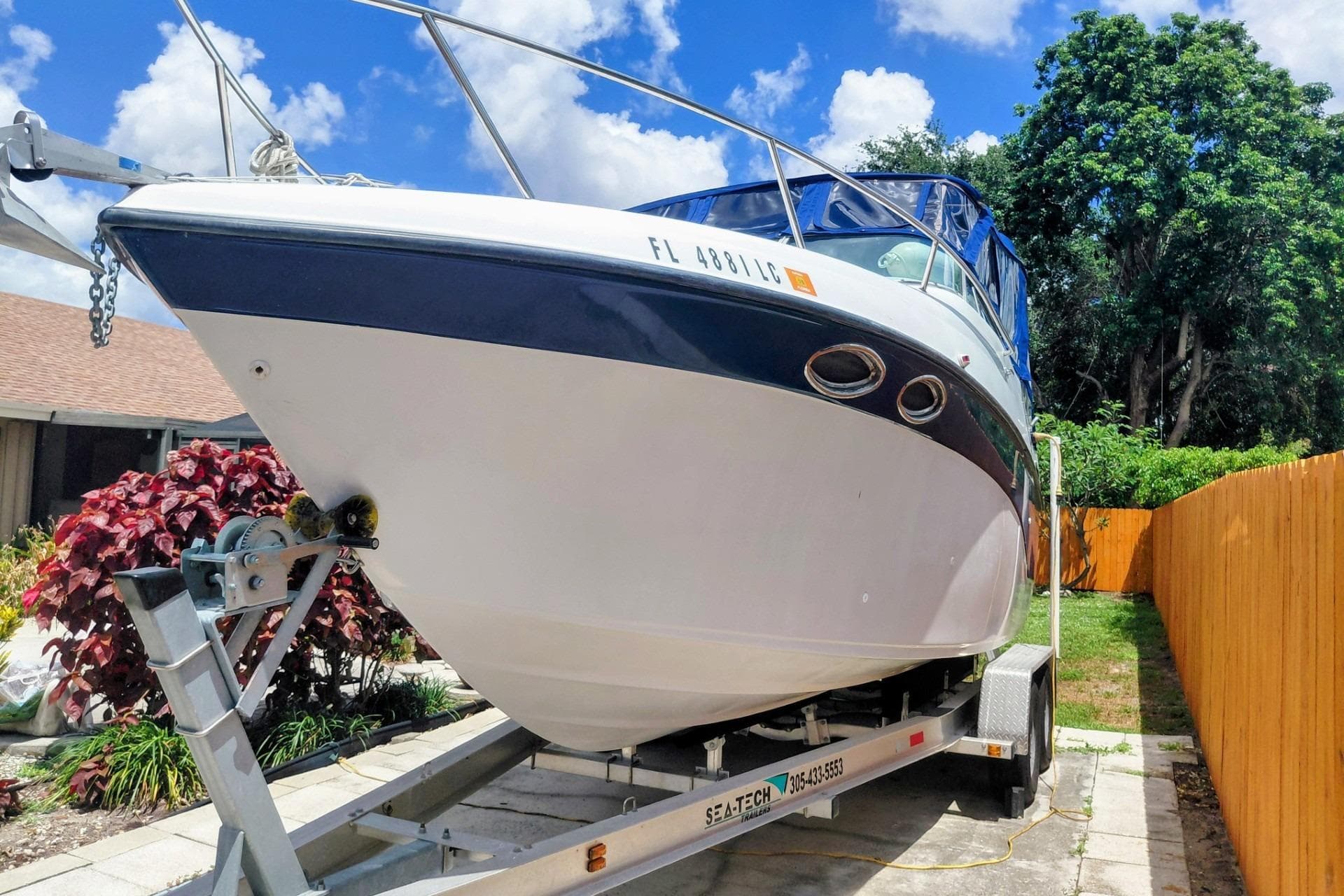 2000 Crownline 242 CR boat on trailer, parked outdoors with blue sky background.