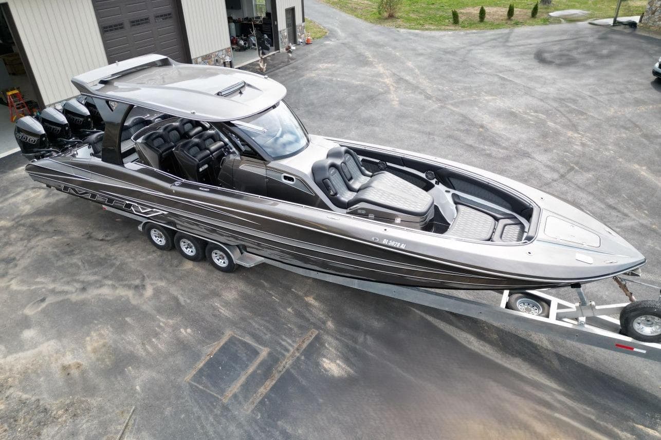 2018 MTI V42 boat on trailer, sleek design, multiple outboard engines, parked near garage.