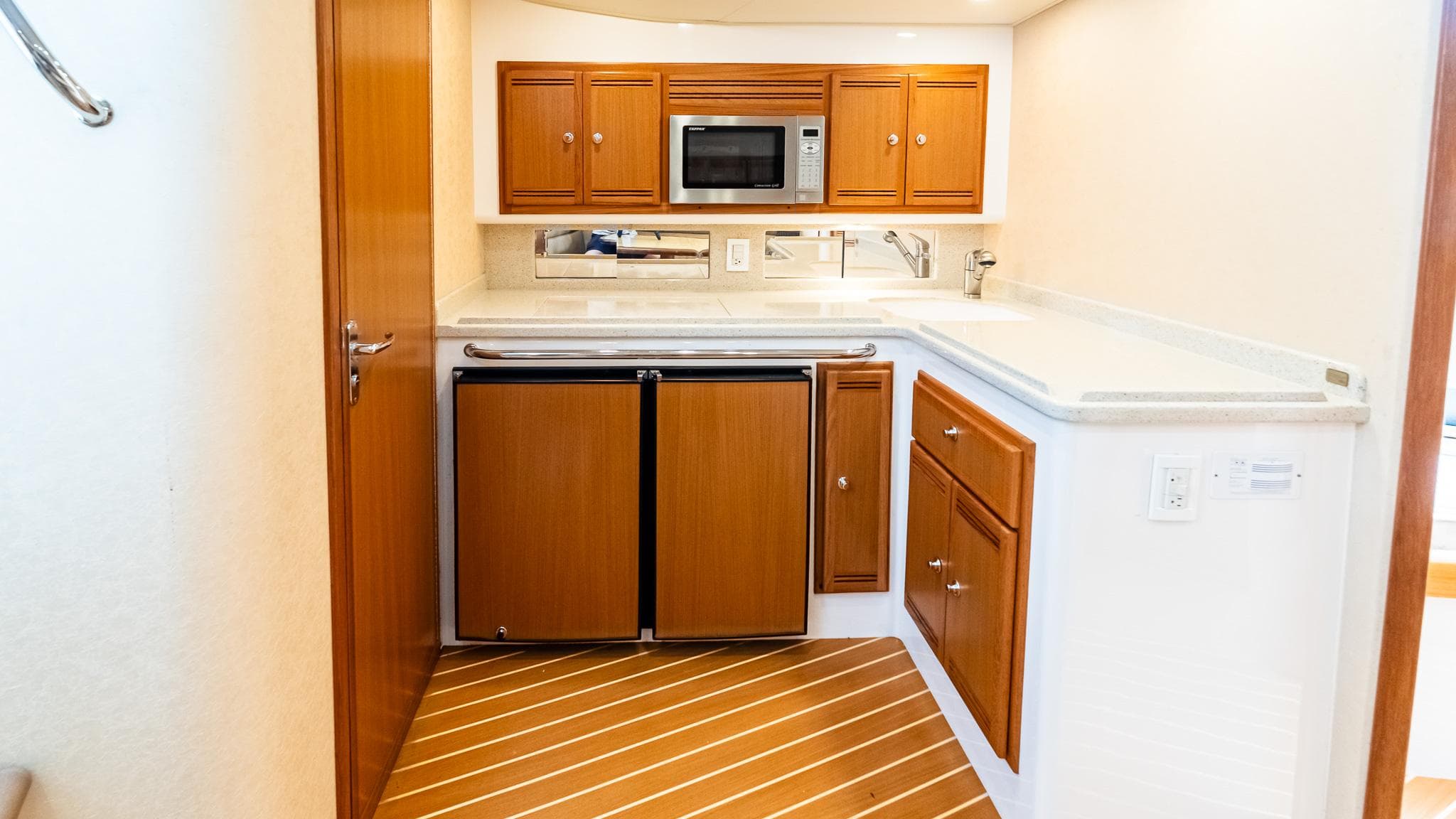 2008 Cabo 38 Express yacht kitchen with wooden cabinets, microwave, and compact fridge.