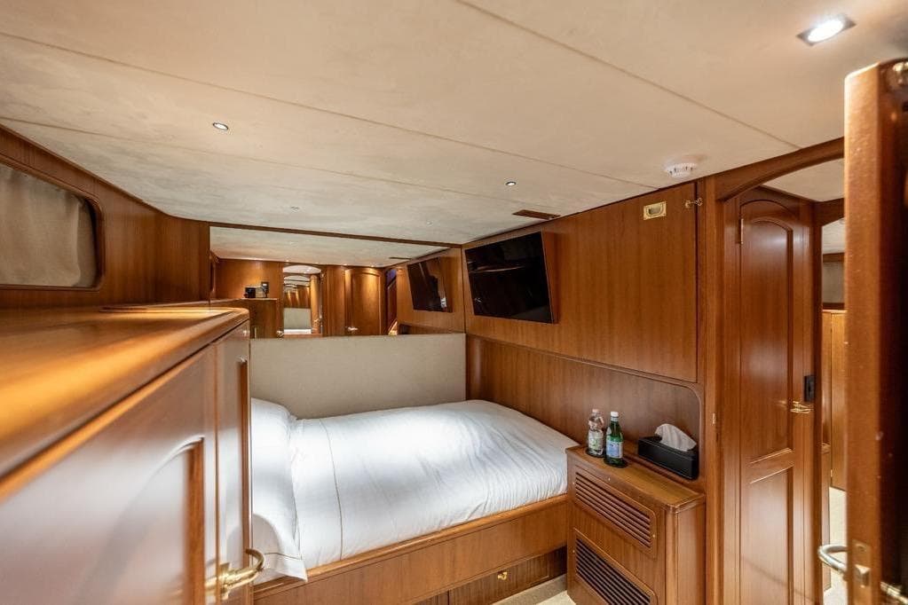 Luxurious cabin interior of 1986 Moonen 85 yacht with wood paneling and cozy bed.