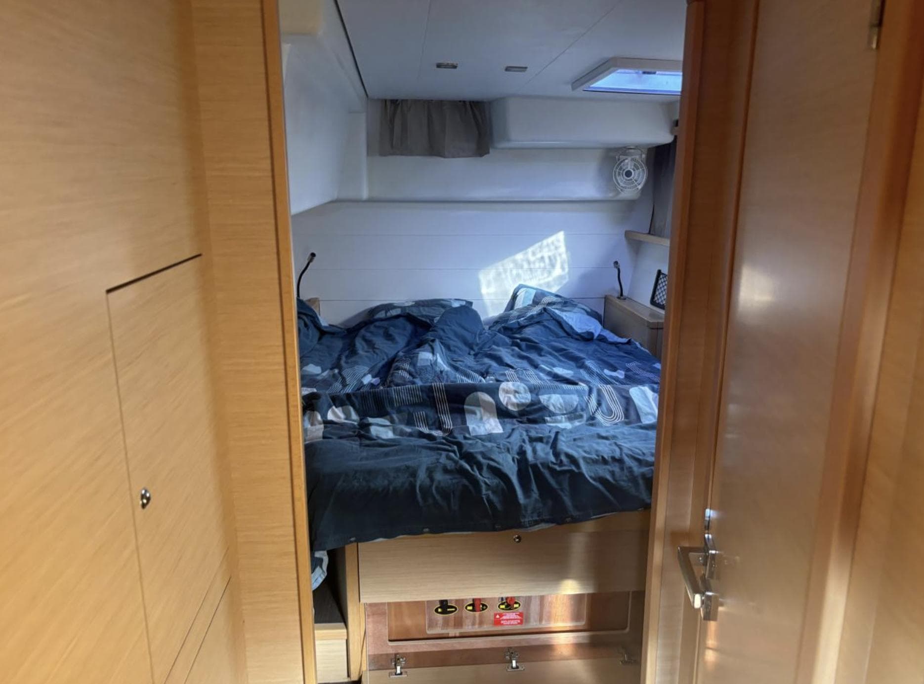 Cozy bedroom interior of 2016 Lagoon 450 F catamaran with natural light and wooden finishes.