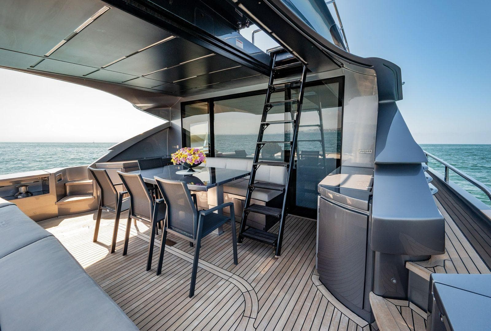 Luxurious 2019 Pershing 82 yacht deck with dining area, ocean view, and modern design.