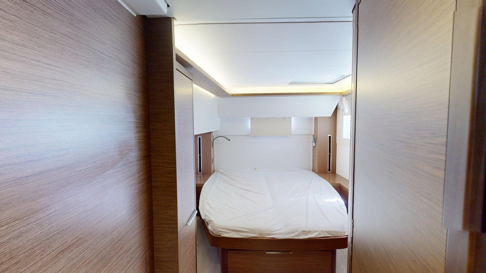 Interior cabin of 2020 Lagoon 46 yacht with modern wood finish and cozy bed.