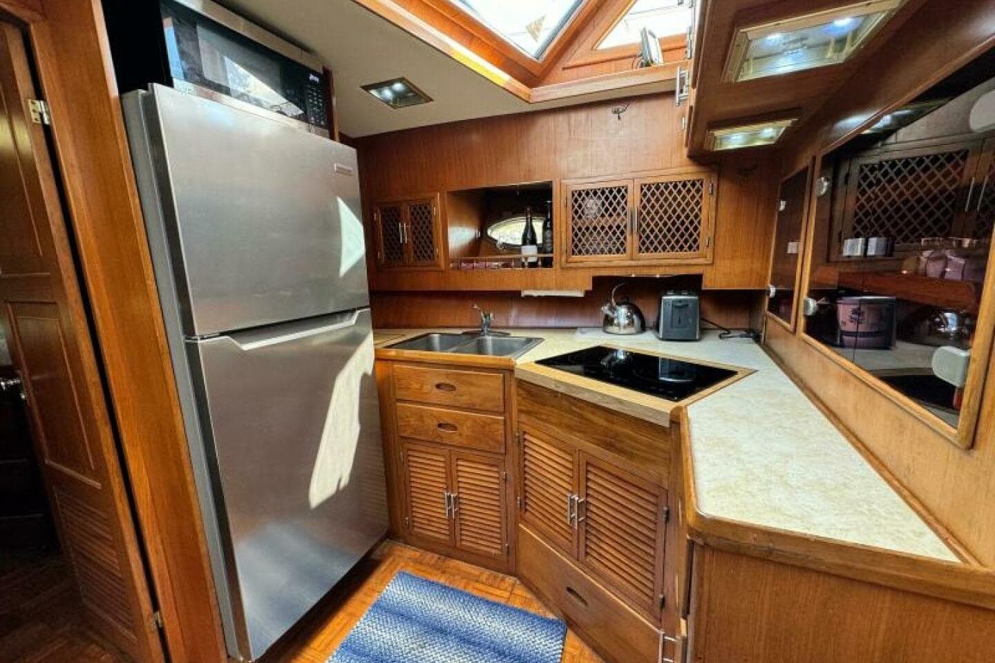 1987 Marine Trader 47 Tradewinds yacht kitchen with stainless steel appliances and wooden cabinetry.