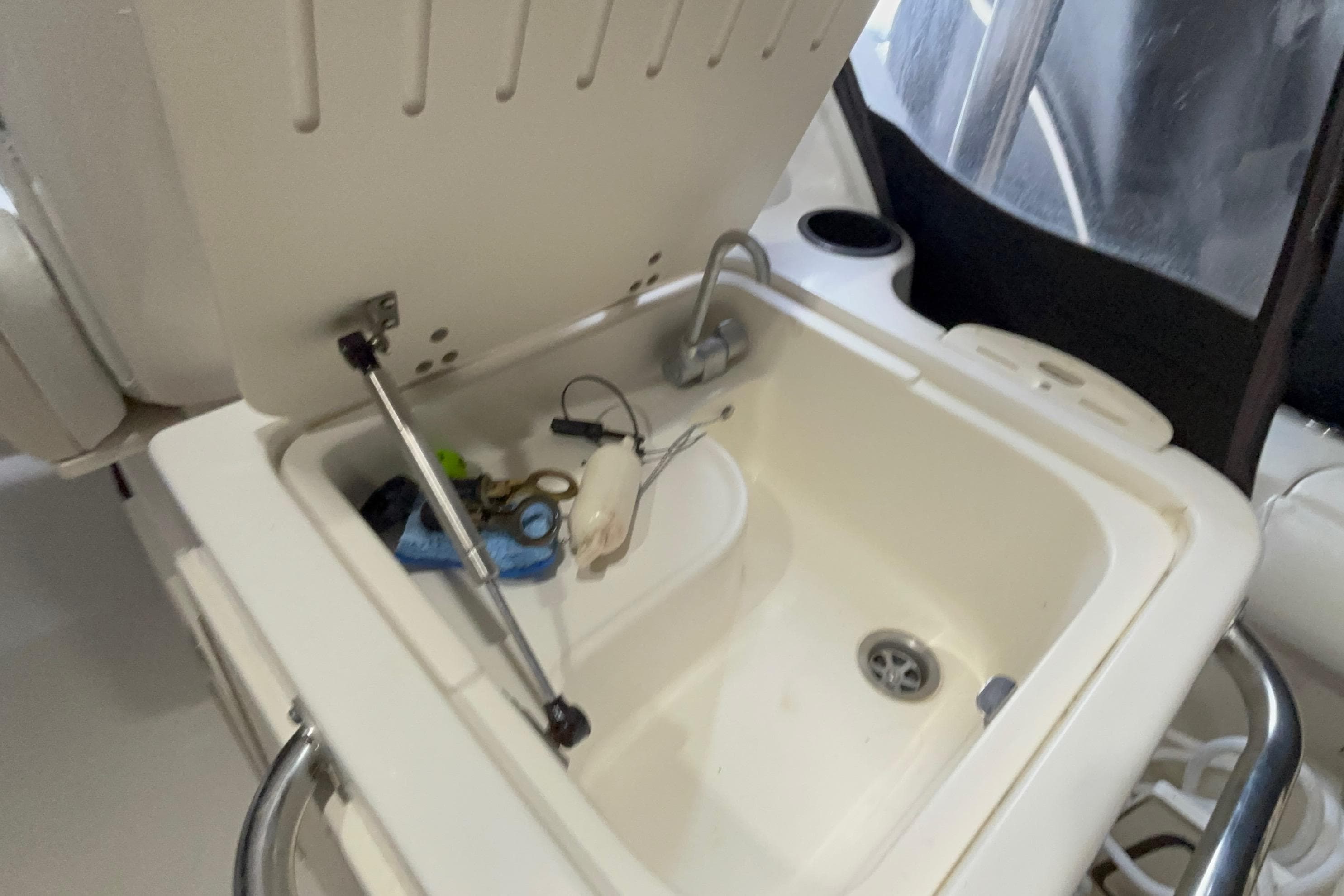 Open storage compartment on 2005 Boston Whaler 305 Conquest boat, showing various small items.