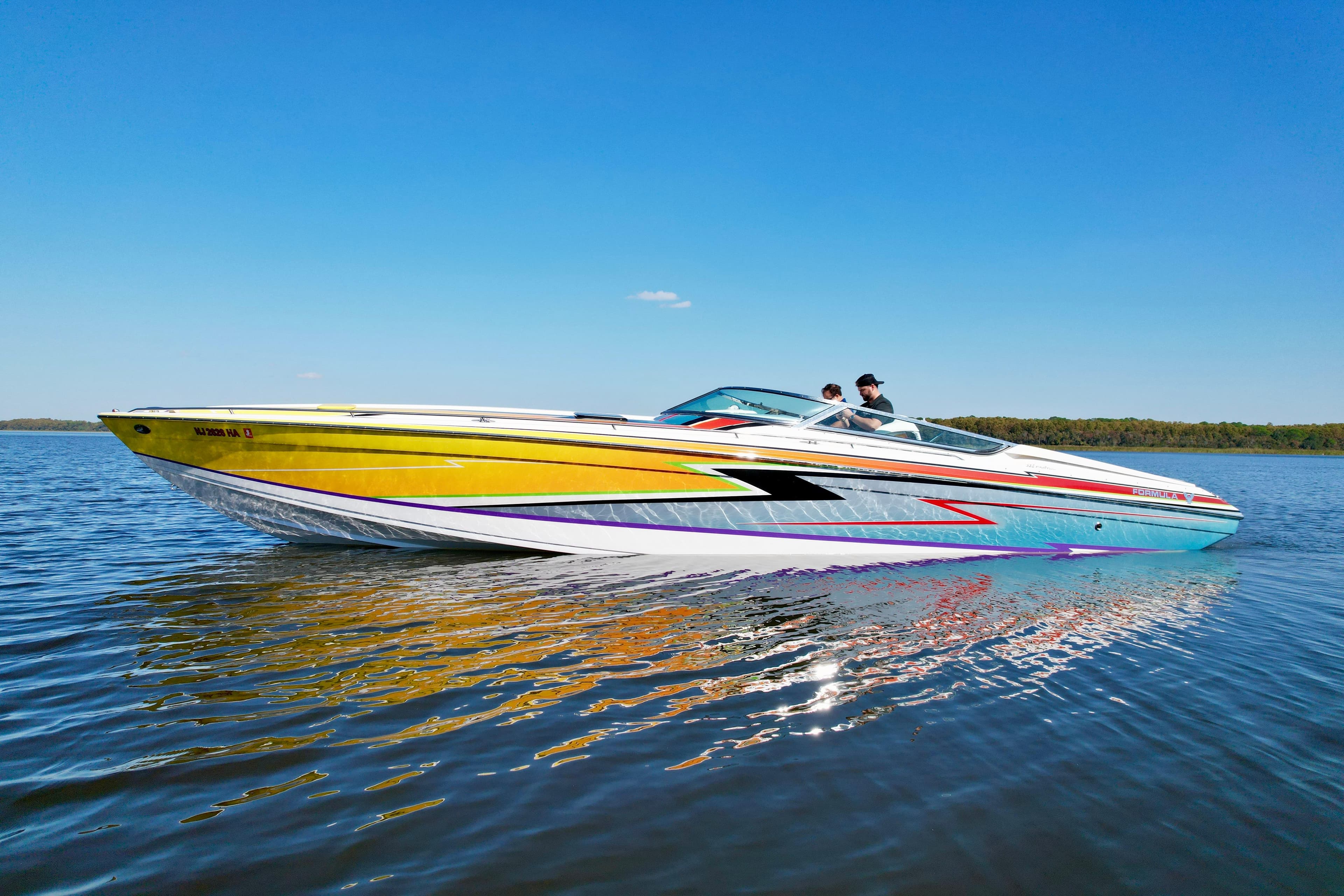 2006 Formula 382 FASTech speedboat with vibrant graphics cruising on a calm lake.