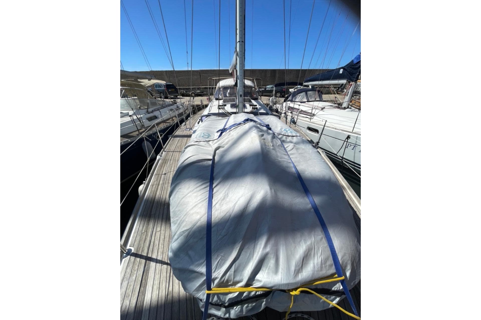 2015 Jeanneau Sun Odyssey 50 DS sailboat deck with covered equipment, docked in marina.