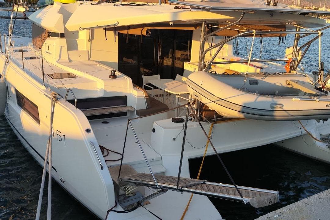 2024 Lagoon 51 yacht docked with inflatable boat on deck at sunset.