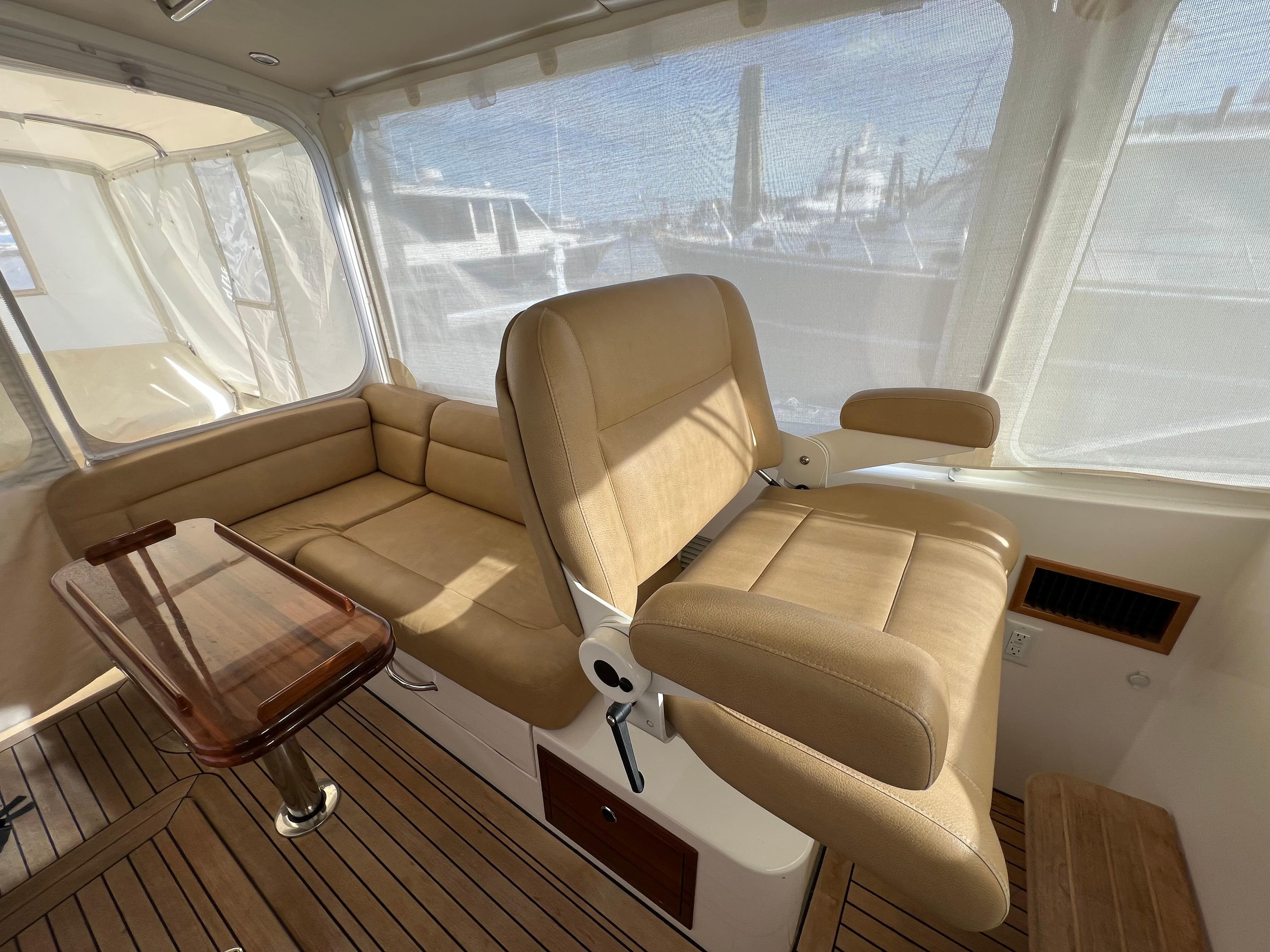 Interior of 2013 MJM 40z Downeast boat with beige seating and wooden flooring.