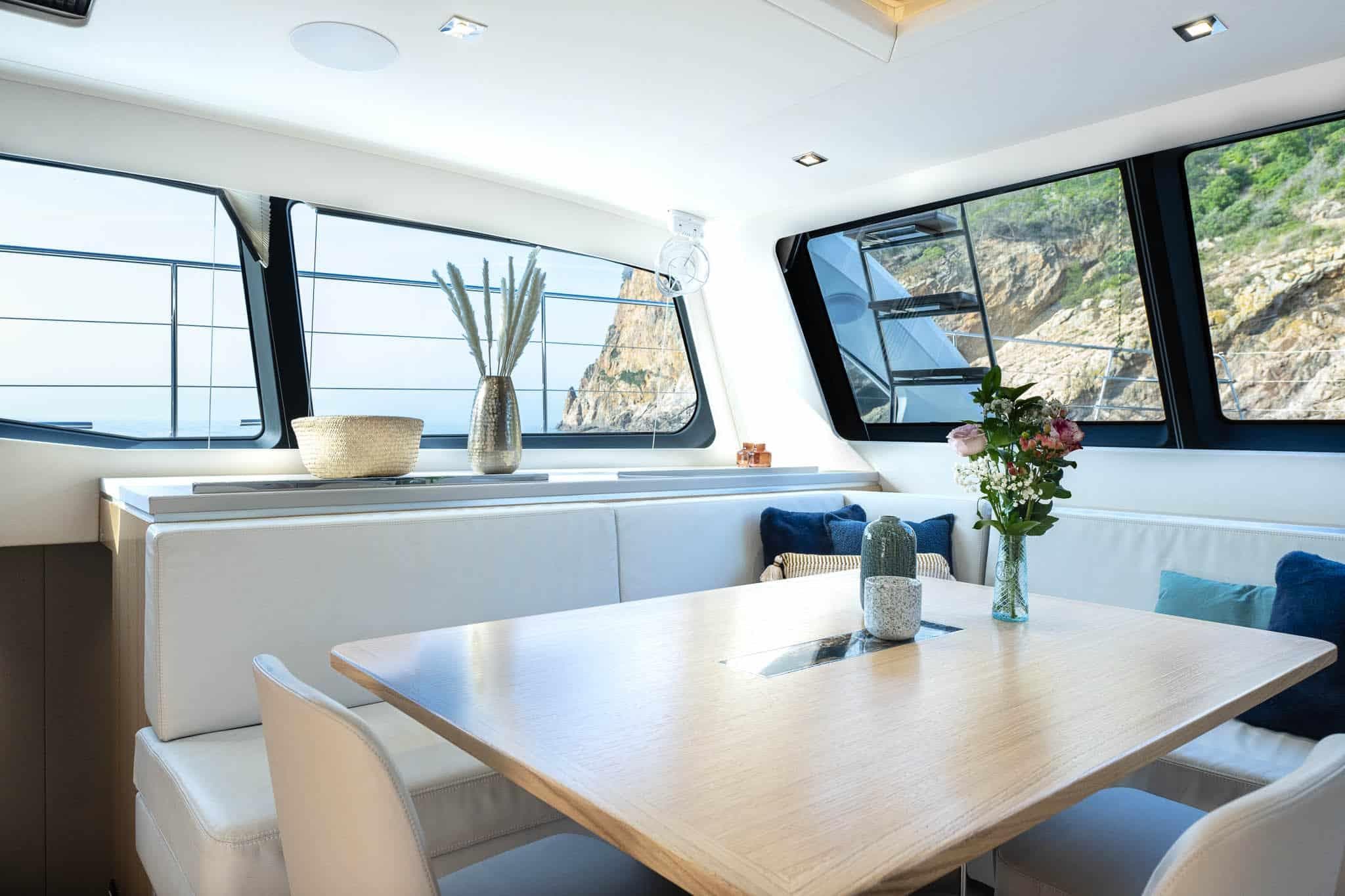 Luxurious interior of 2025 Privilege Signature 580 yacht with elegant dining area and scenic views.