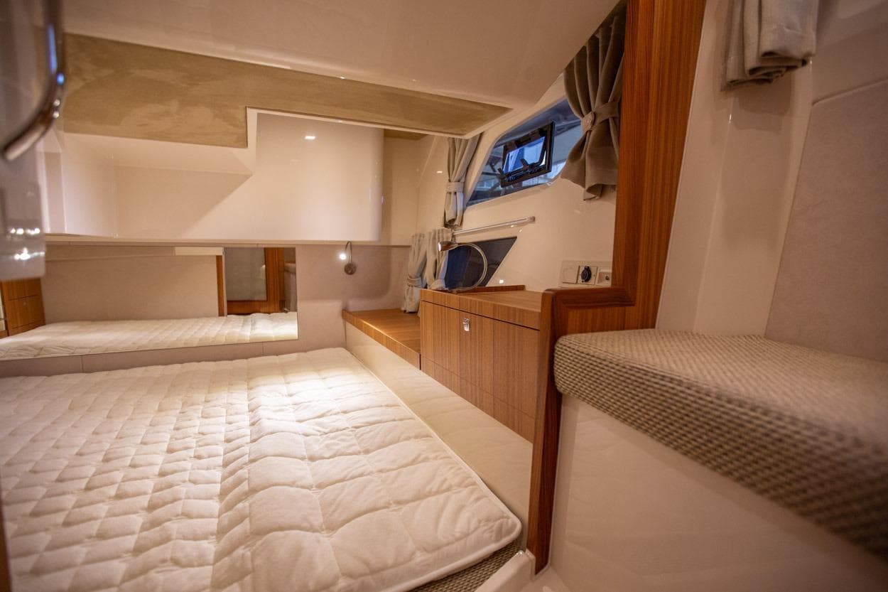 Interior cabin of 2022 Marex 360 Cabriolet Cruiser, featuring cozy bedding and wooden accents.